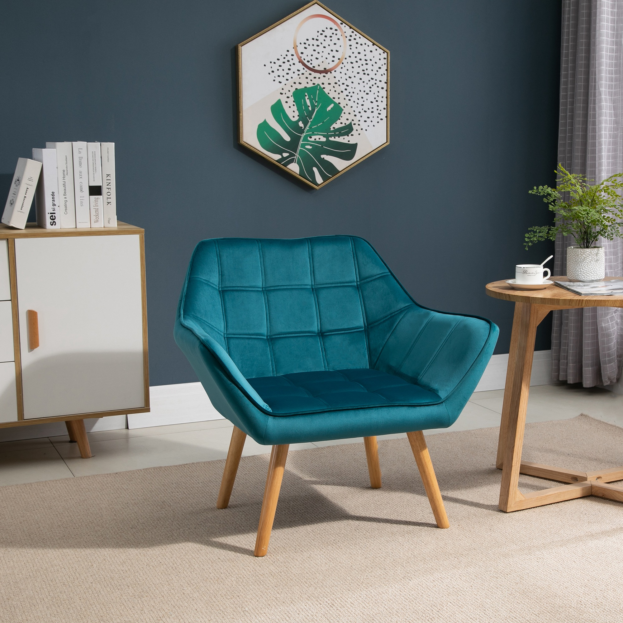 Una poltrona blu con gambe in legno in una stanza con pareti scure e un quadro appeso.
