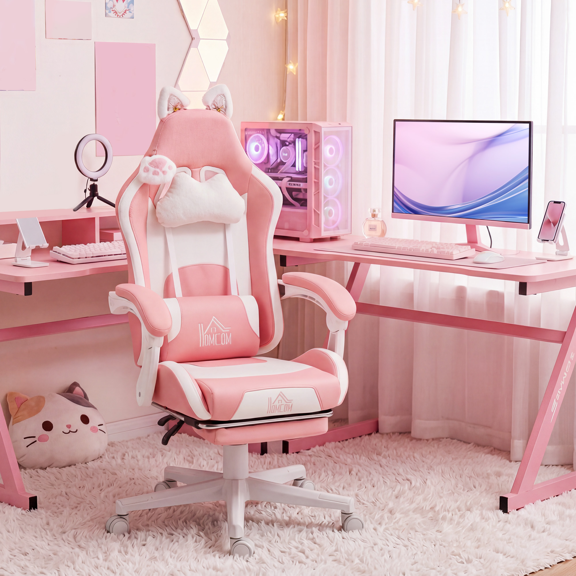 Una postazione da gioco rosa con scrivania, PC, monitor e una sedia ergonomica con orecchie di gatto su un tappeto soffice.