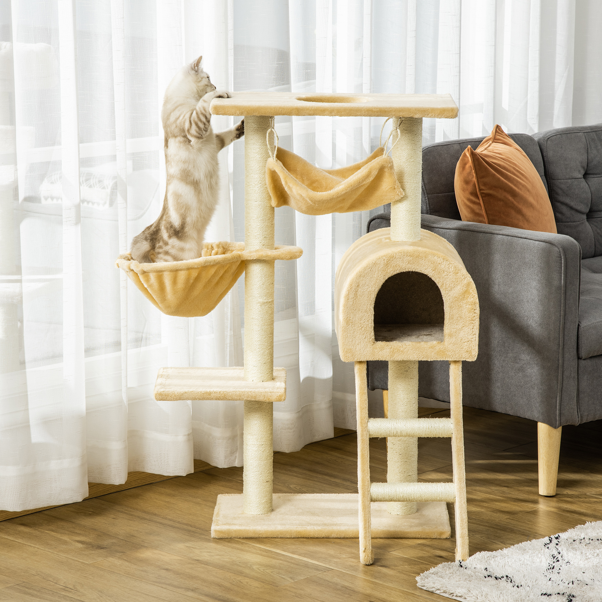 Un gatto grigio si stiracchia su un tiragraffi beige in un soggiorno vicino a un divano.
