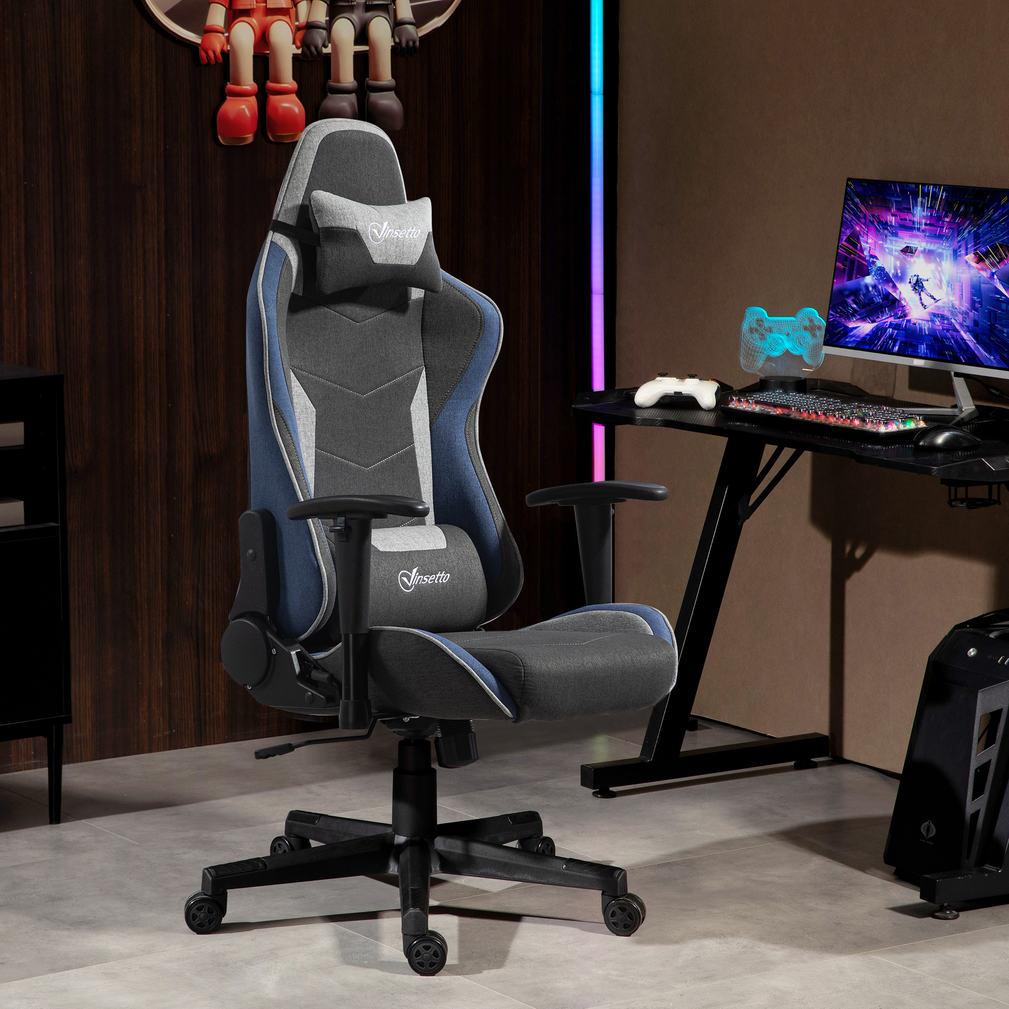 Sedia da gaming grigia e blu con poggiatesta davanti a una scrivania con monitor e accessori colorati.