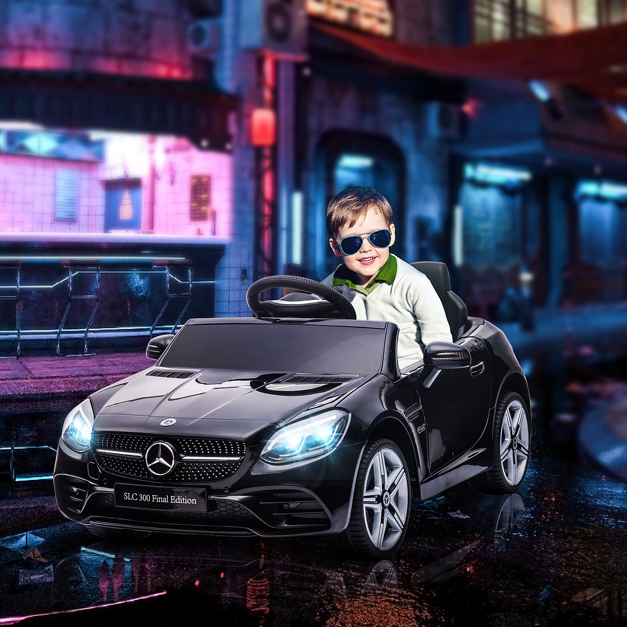 Un bambino con gli occhiali da sole guida un'auto giocattolo Mercedes nera su una strada.