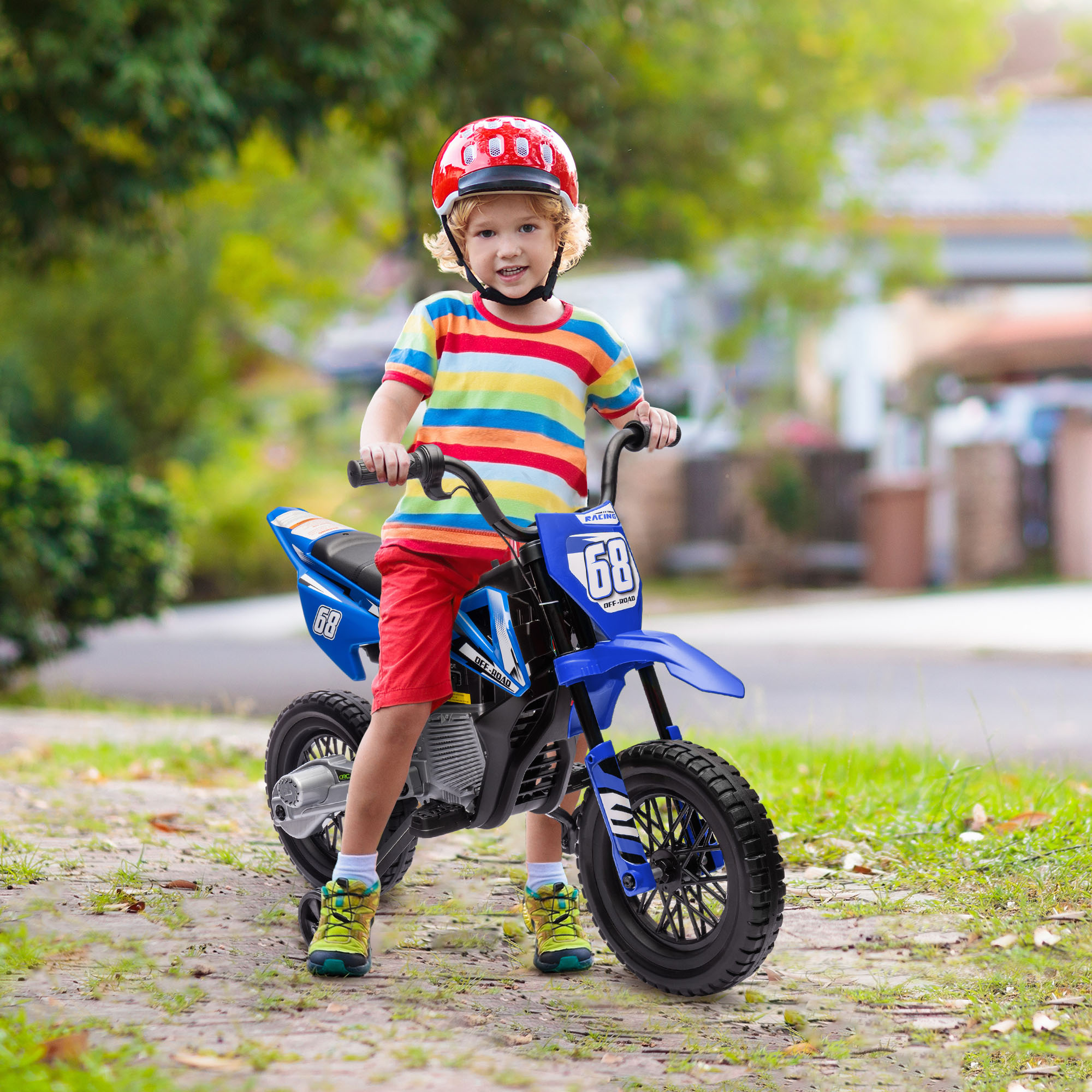 Un bambino con casco rosso siede su una moto giocattolo blu all'aperto.