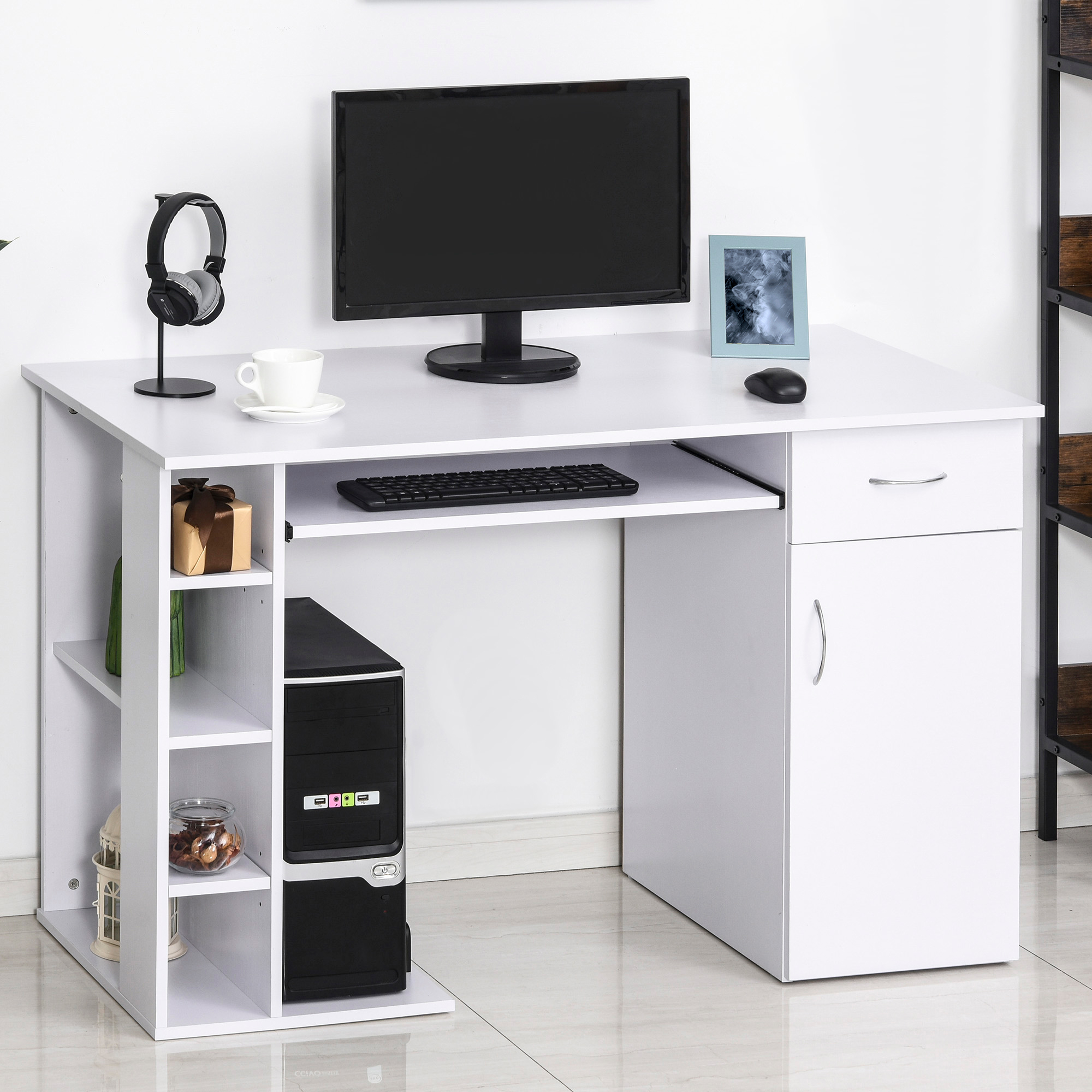 Una scrivania bianca per computer con torre nera, monitor, tastiera, cuffie e ripiani su pavimento chiaro.
