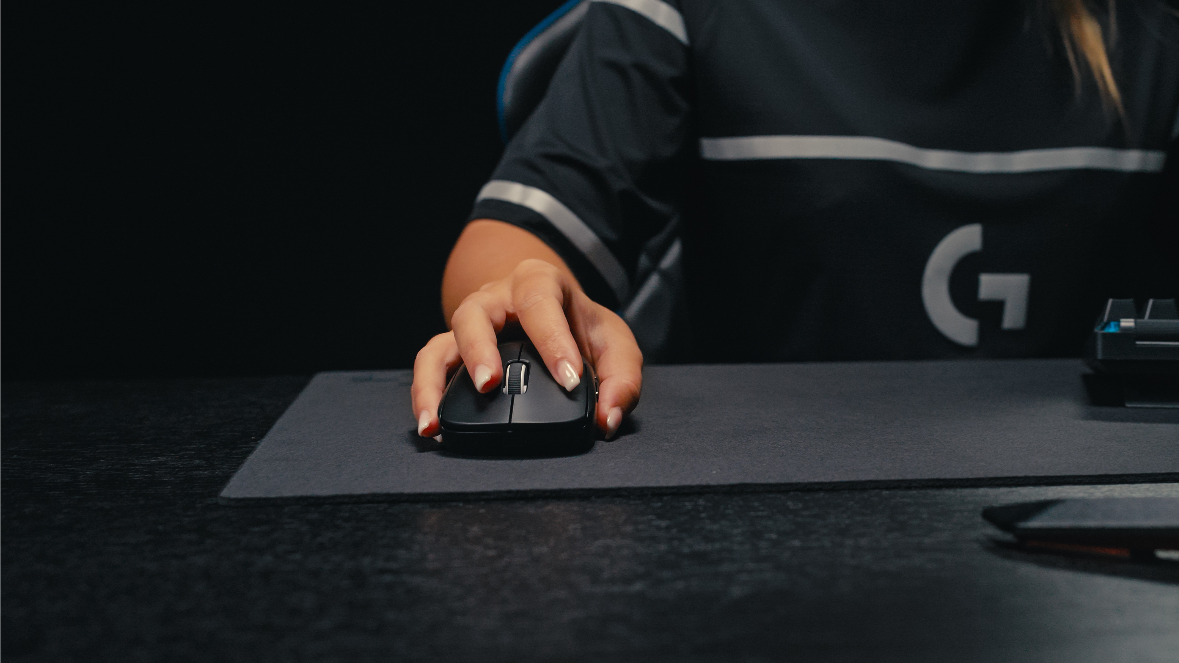 Una mano impugna un mouse per computer nero su un tappetino.
