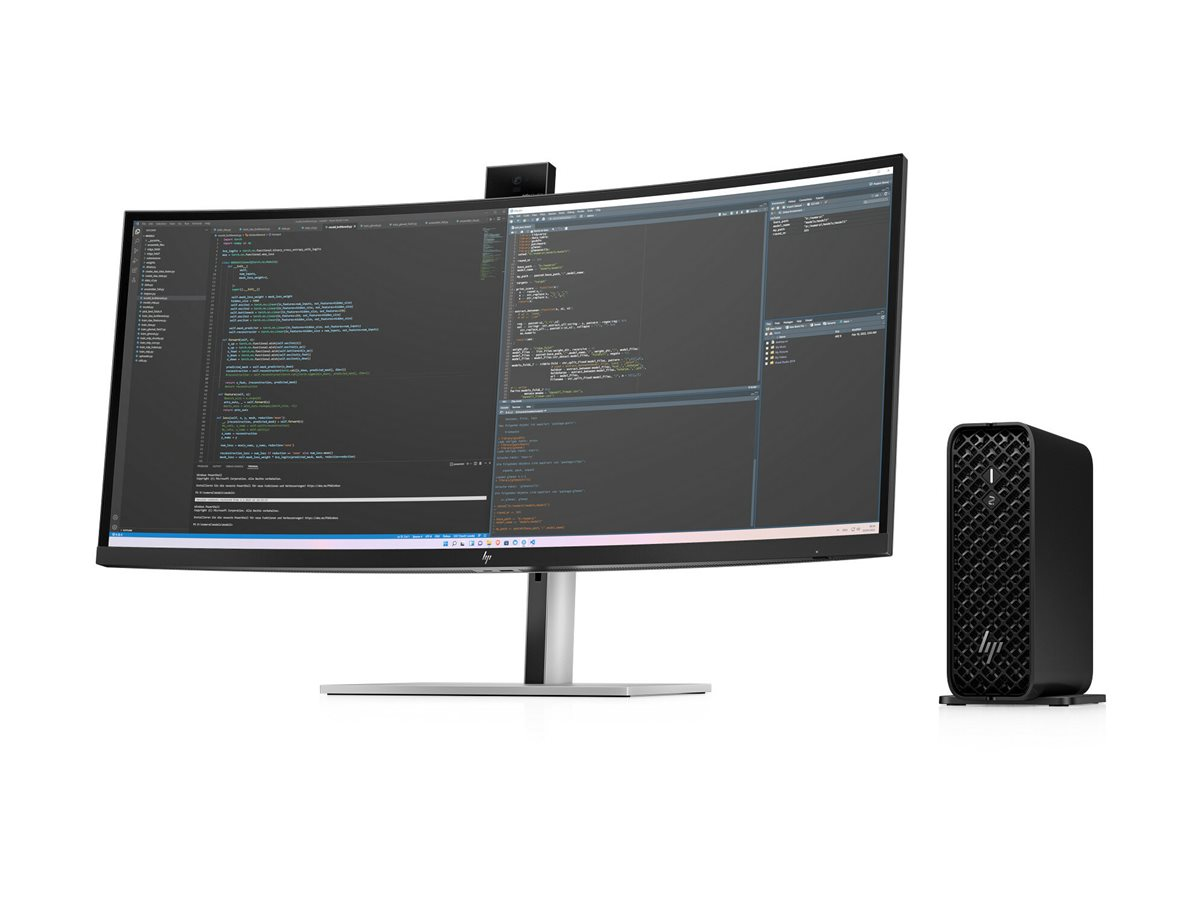 Ein breiter, gebogener Monitor mit Programmiercode auf dem Bildschirm steht neben einem kompakten schwarzen PC.