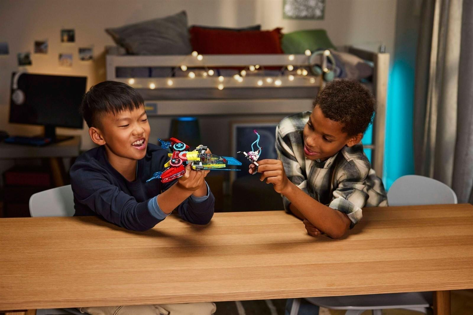 Zwei Jungs spielen glücklich an einem Holztisch mit bunten Lego-Raumschiffen in ihrem Jugendzimmer.