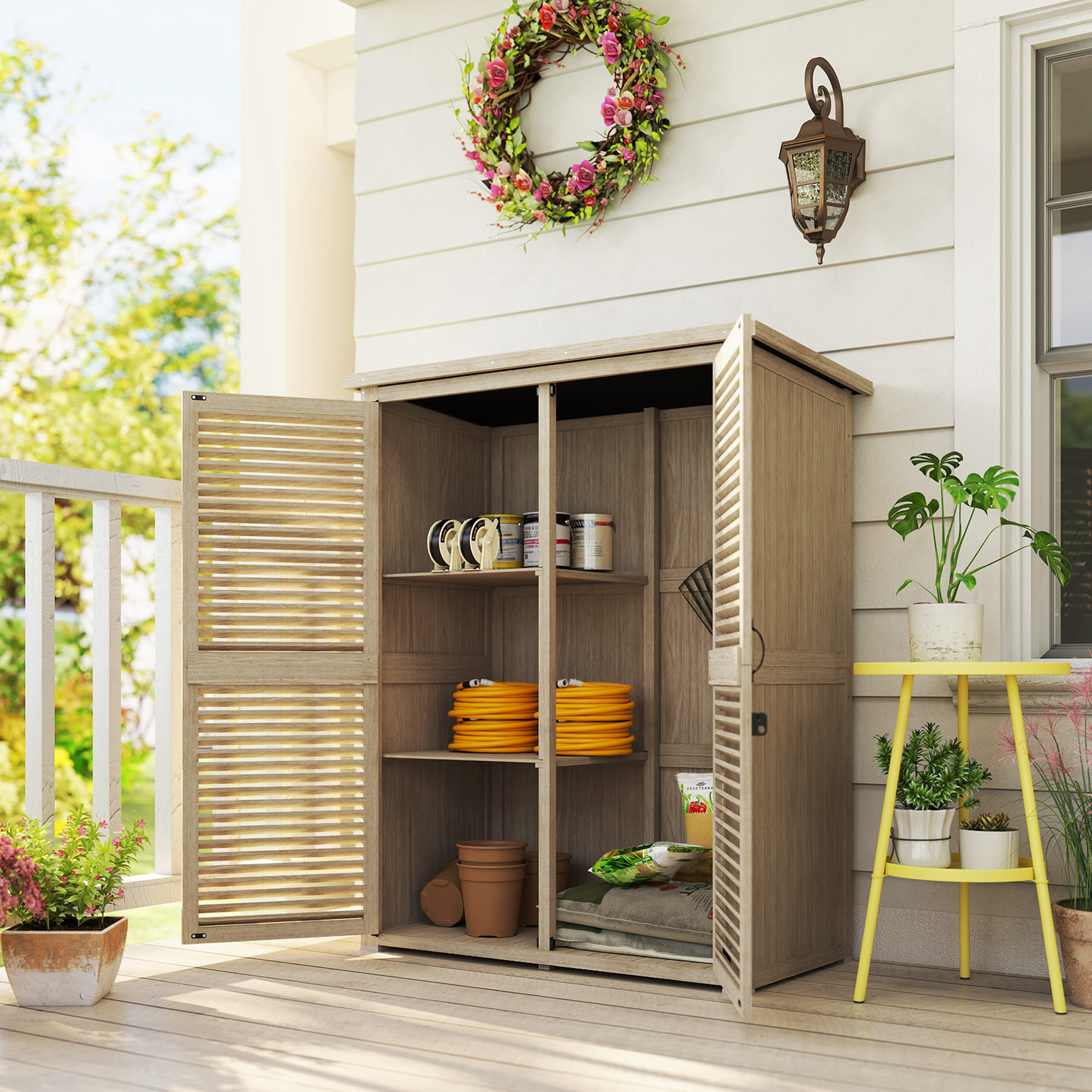 Un mobile da giardino in legno aperto su un portico contiene attrezzi e tubi gialli.