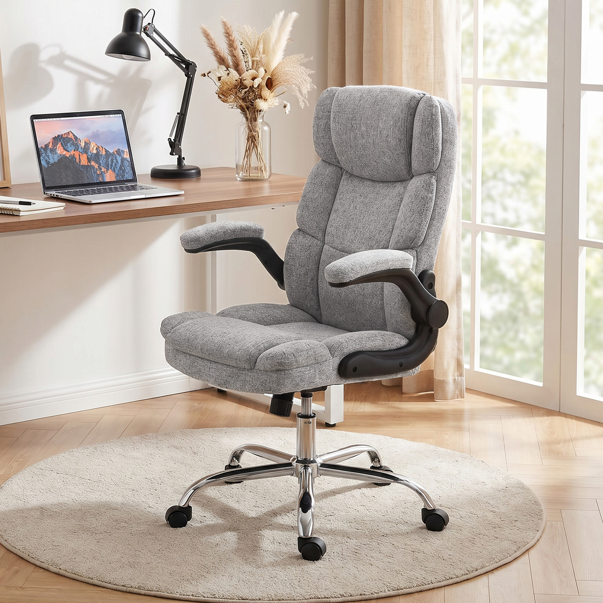 Sedia da ufficio ergonomica grigia con braccioli neri su tappeto rotondo in una stanza luminosa.