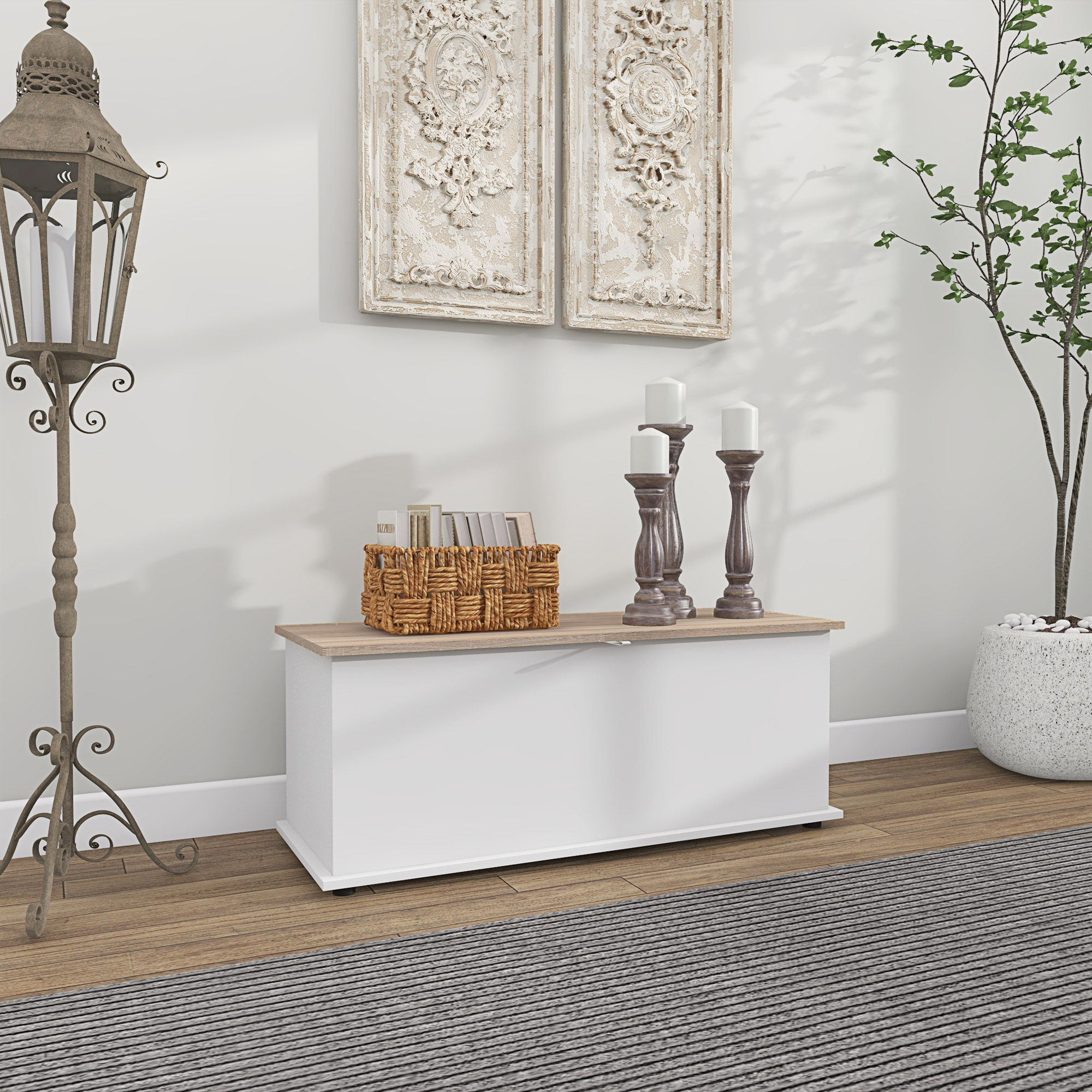 Una panca contenitore bianca con piano in legno, decorata con candele, un cestino e quadri.