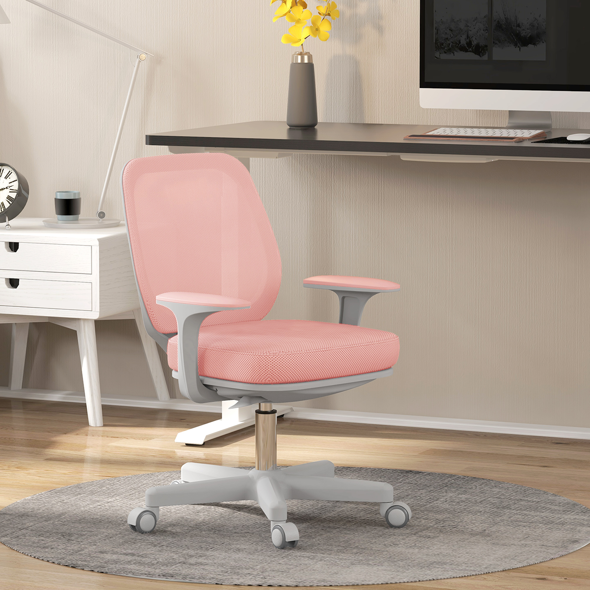 Una sedia da ufficio rosa in rete su un tappeto grigio davanti a una scrivania e lampada.
