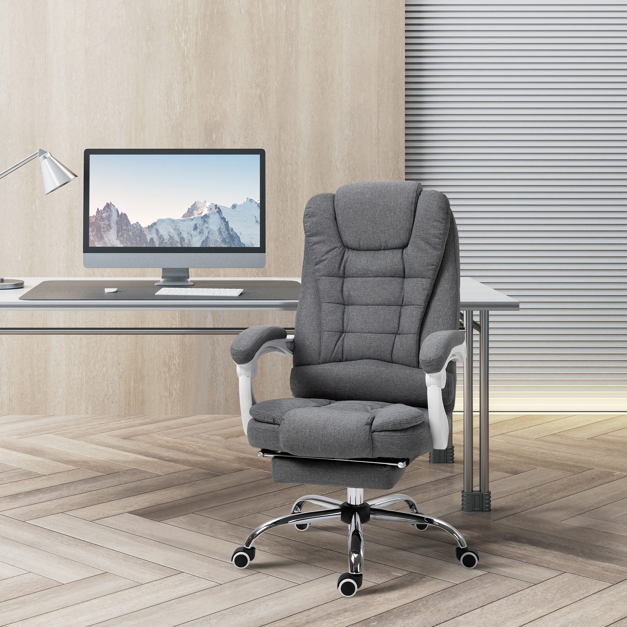 Una sedia da ufficio grigia davanti a una scrivania con monitor in una stanza moderna.