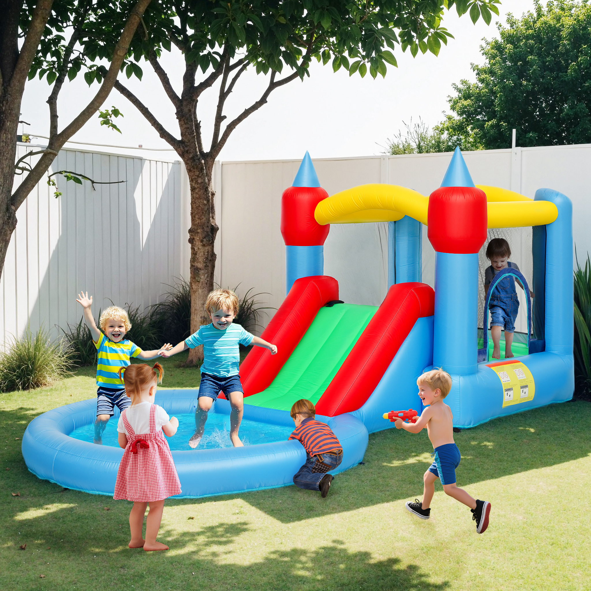 I bambini giocano vicino a un colorato castello gonfiabile con scivolo d'acqua e piscina.
