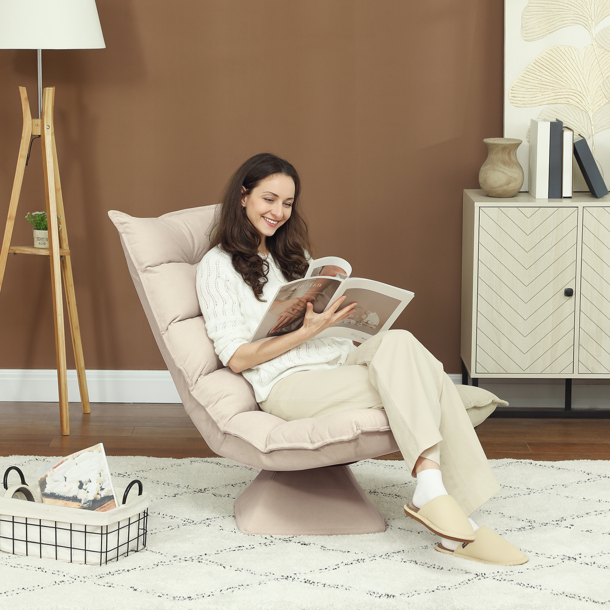 Una donna in abiti bianchi è seduta su una poltrona beige e legge una rivista in una stanza accogliente.