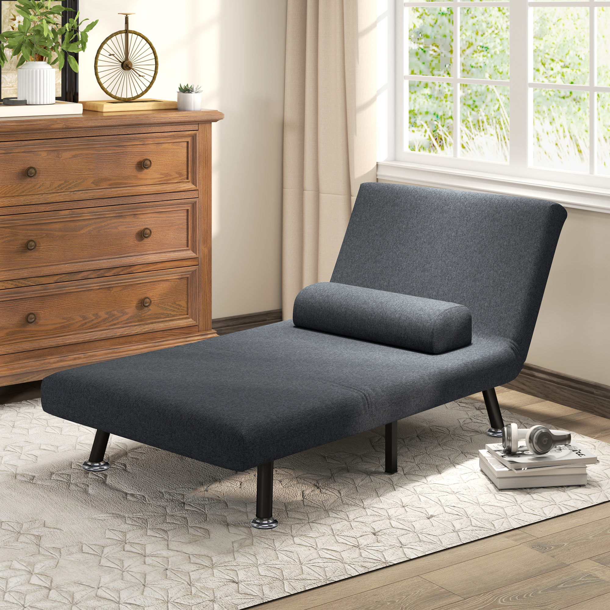 Chaise longue grigio scuro su un tappeto vicino a una cassettiera in legno e una finestra.