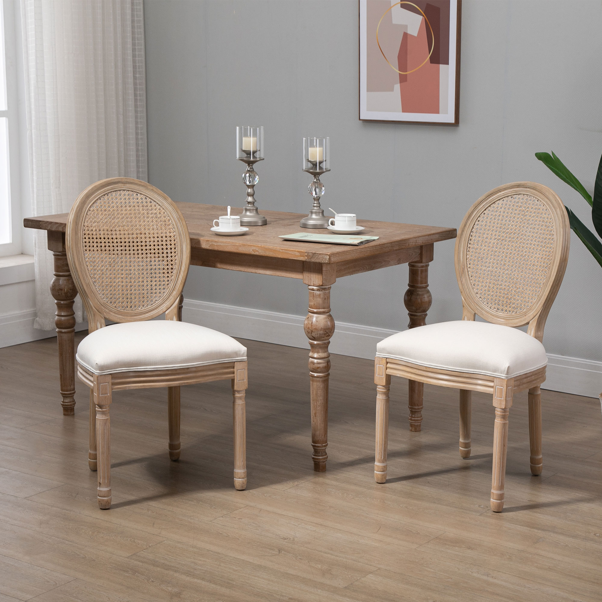 Due sedie da pranzo in legno con schienale in rattan davanti a un tavolo con candelabri.