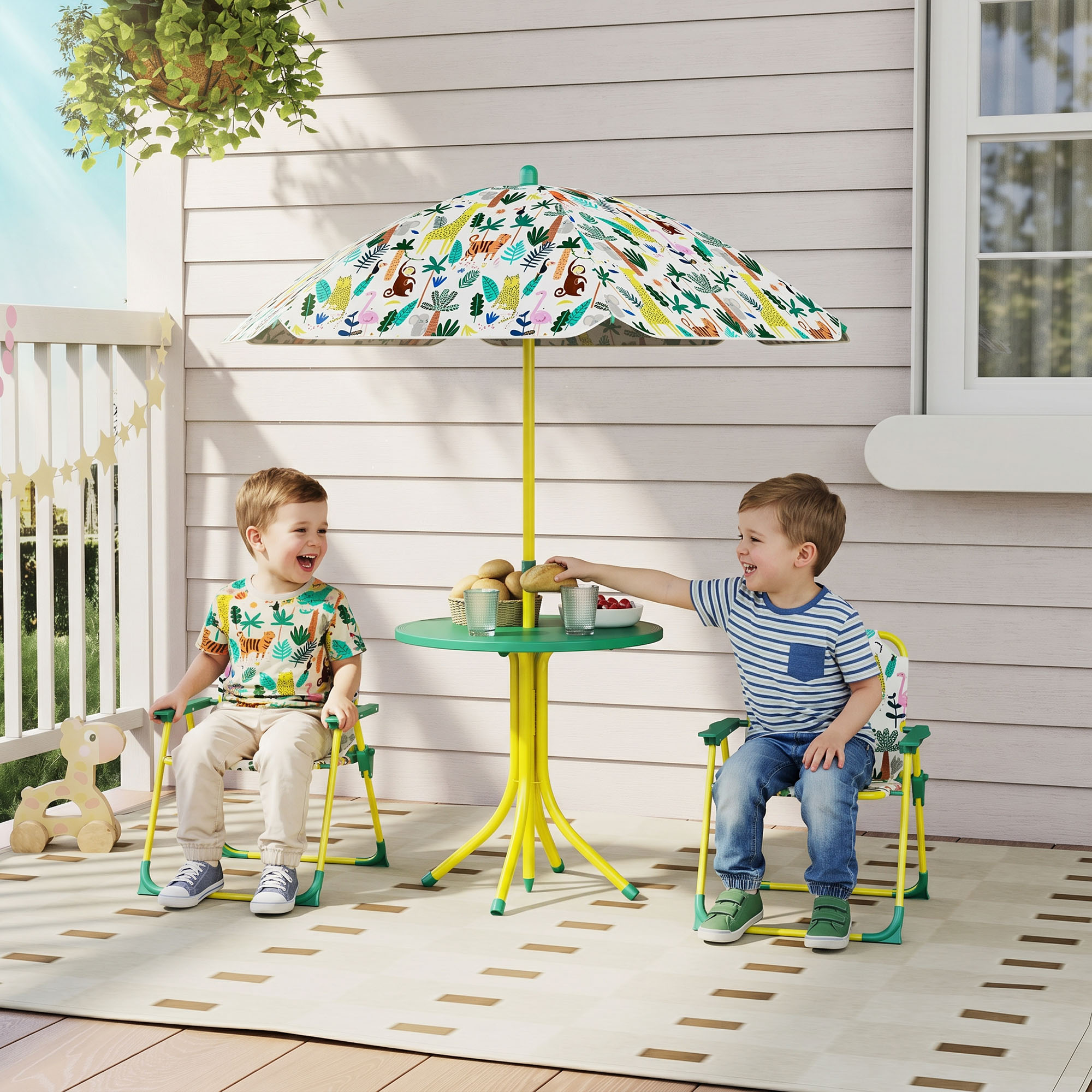 Due bambini ridono seduti a un piccolo tavolo verde con ombrellone fantasia in veranda.