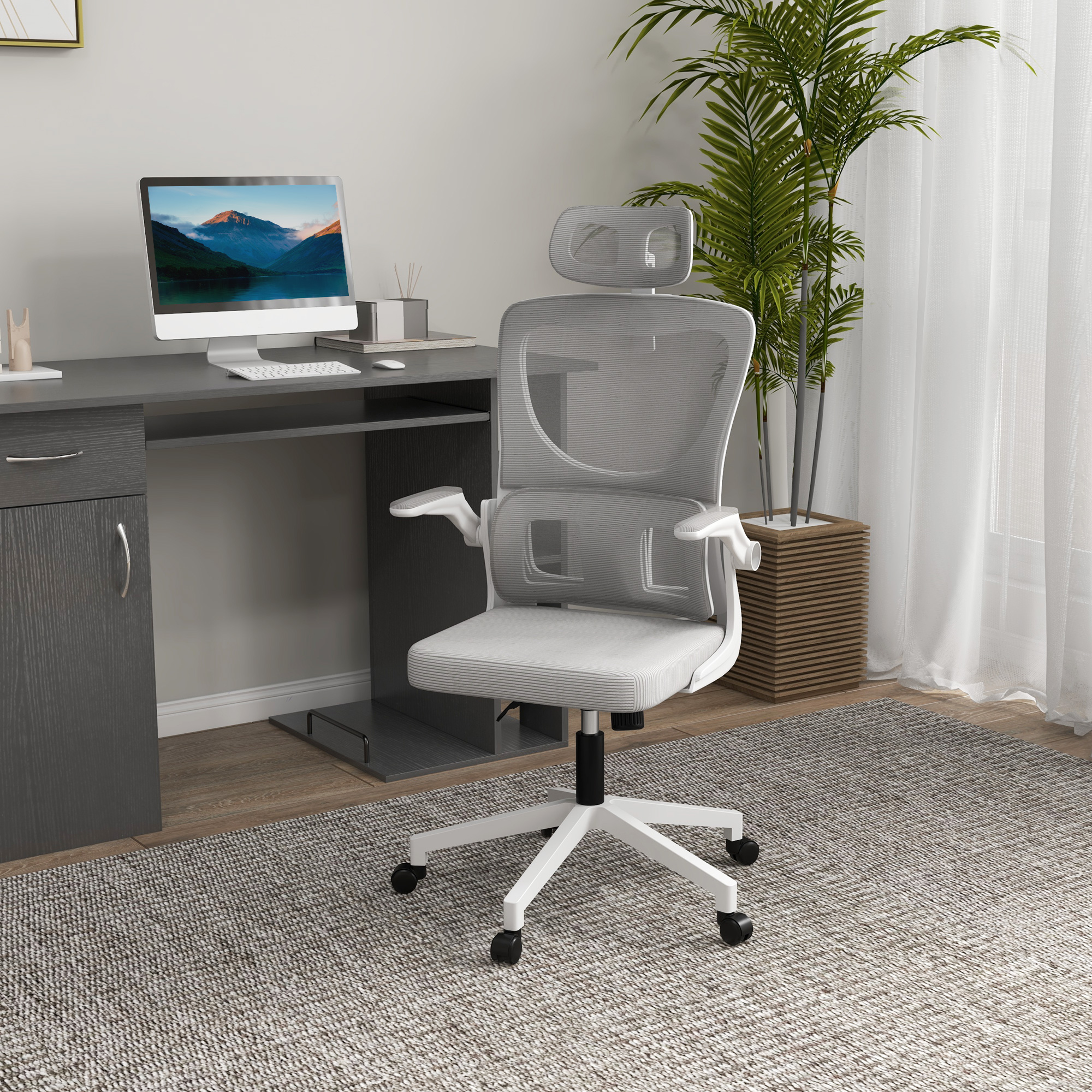 Una sedia da ufficio grigio chiaro con poggiatesta su un tappeto, con scrivania, computer e pianta in vaso sullo sfondo.