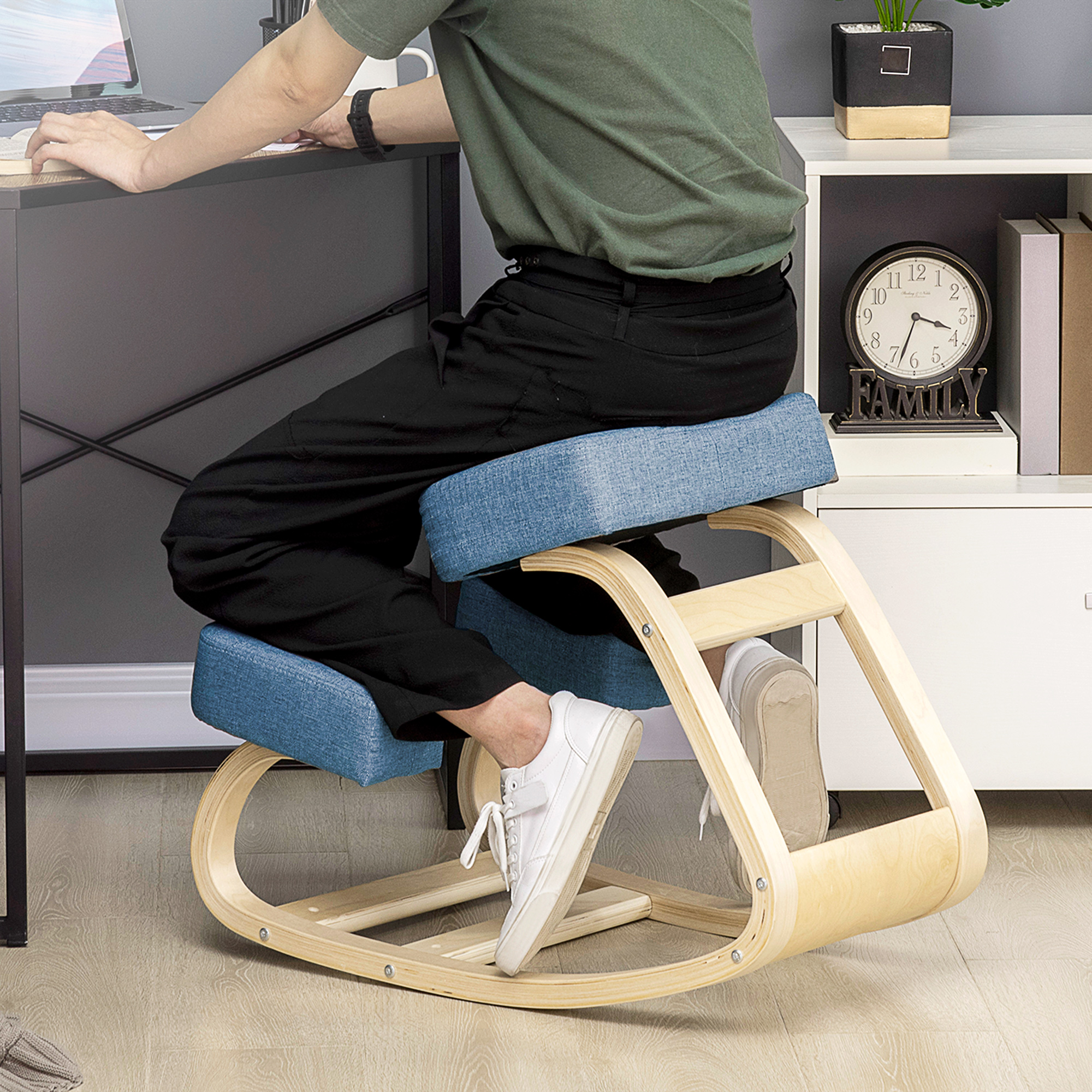 Una persona siede su una sedia ergonomica inginocchiata blu e di legno a una scrivania.