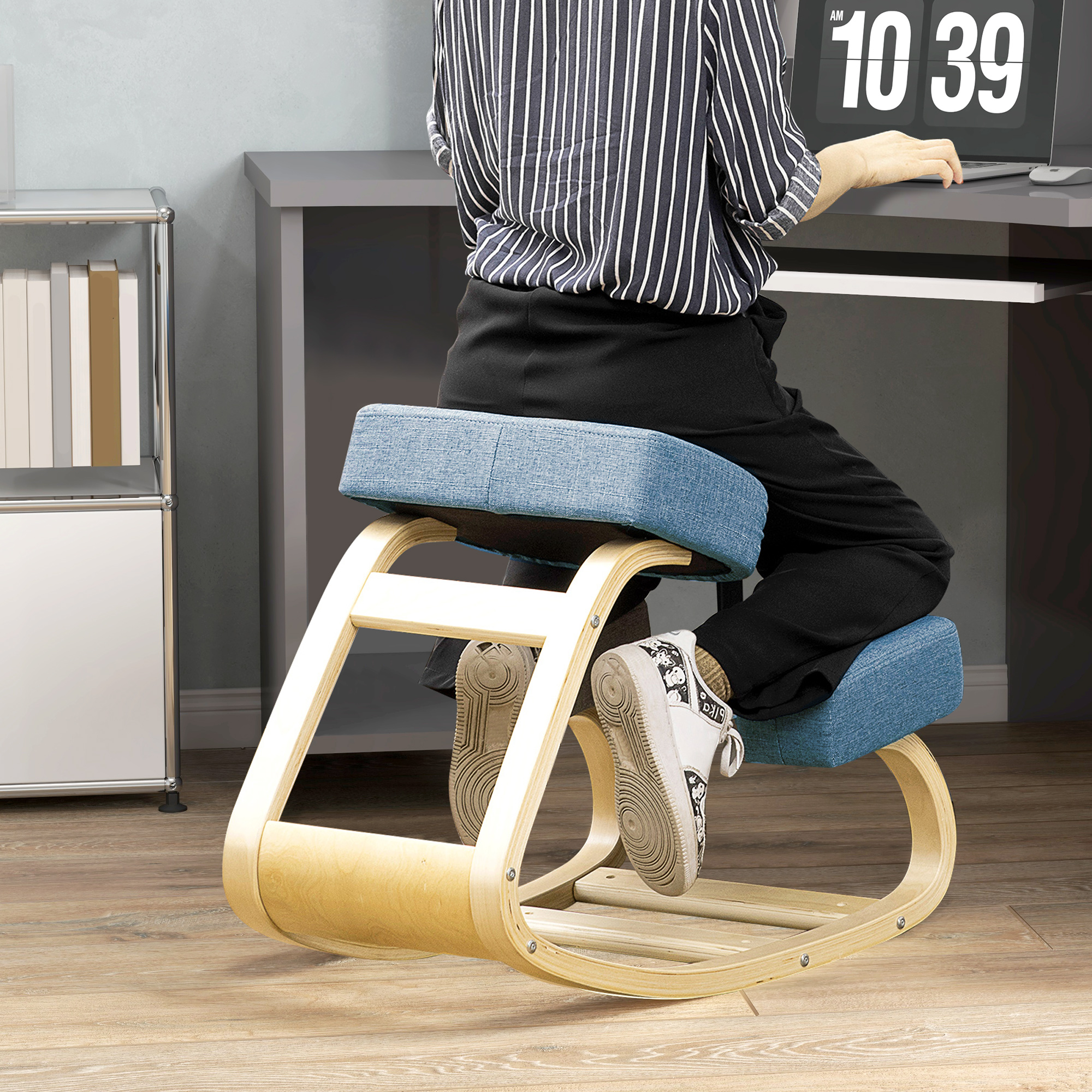 Persona inginocchiata su uno sgabello ergonomico in legno con cuscini blu, che lavora a una scrivania.