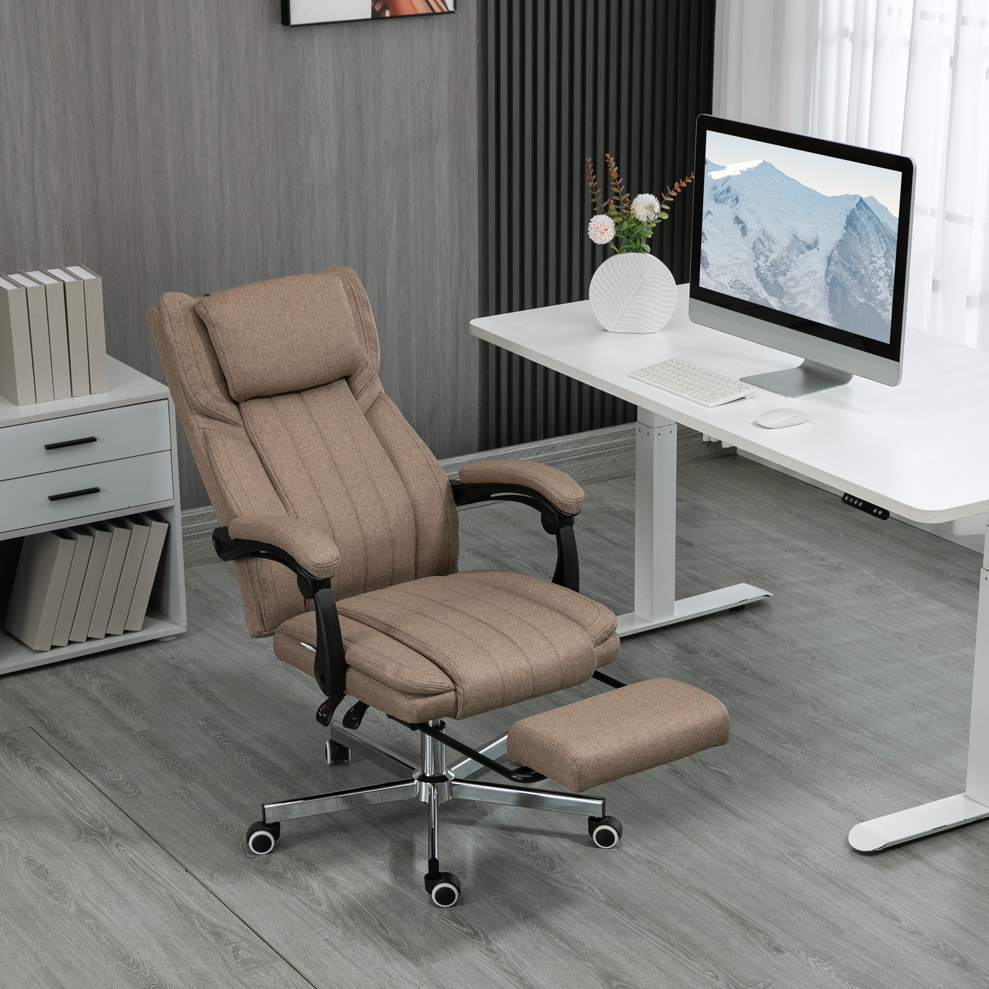 Una sedia da ufficio ergonomica marrone con poggiapiedi davanti a una scrivania bianca con computer.