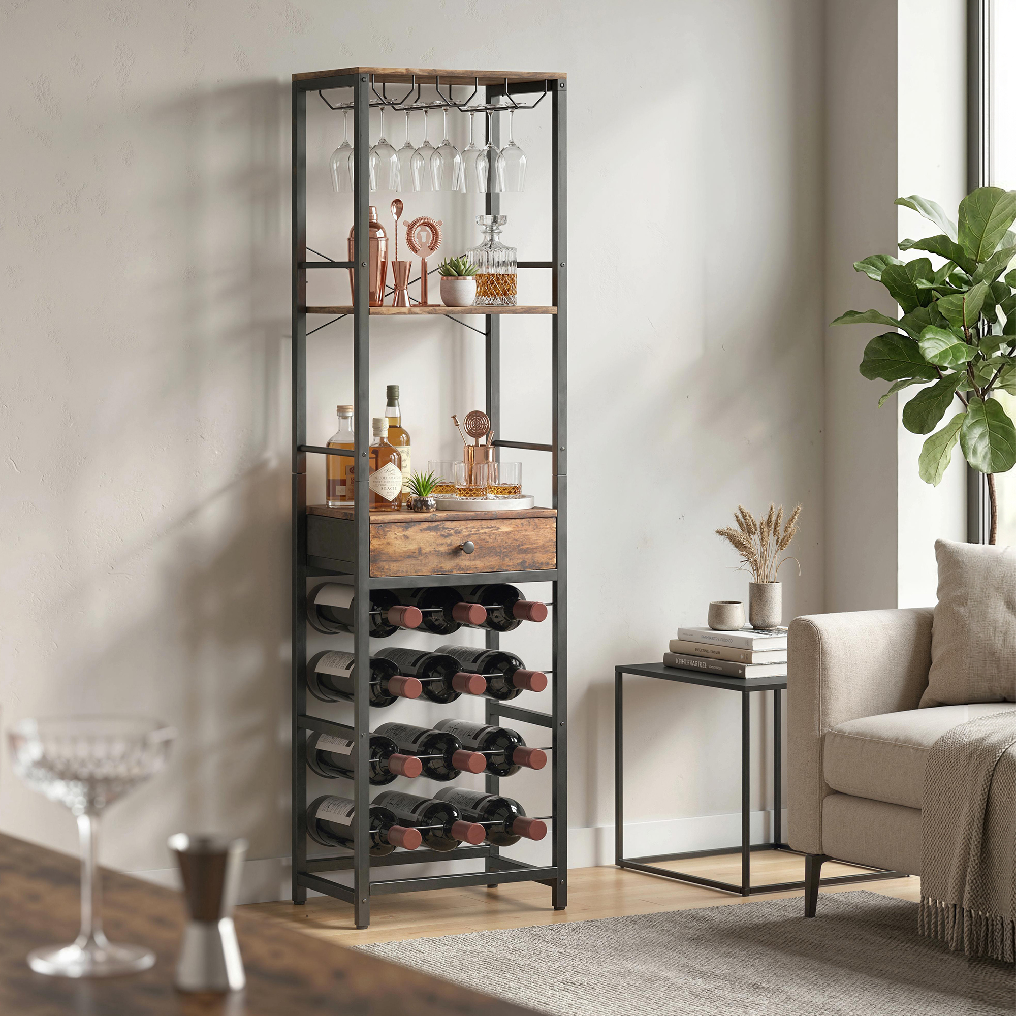 Un mobile bar in metallo e legno con portabottiglie, bicchieri appesi e bottiglie accanto a un divano.