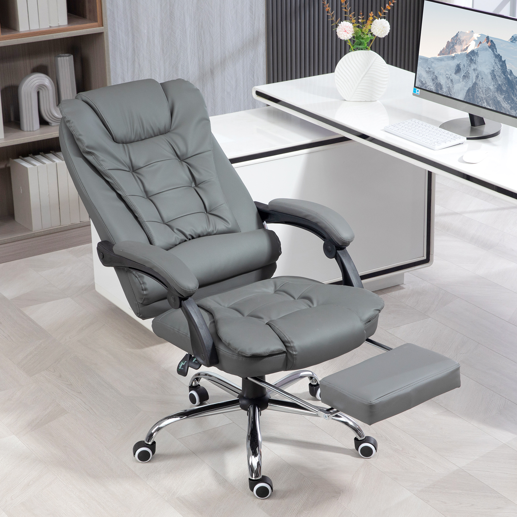 Una sedia da ufficio ergonomica grigia con poggiapiedi estraibile si trova in un ufficio moderno.