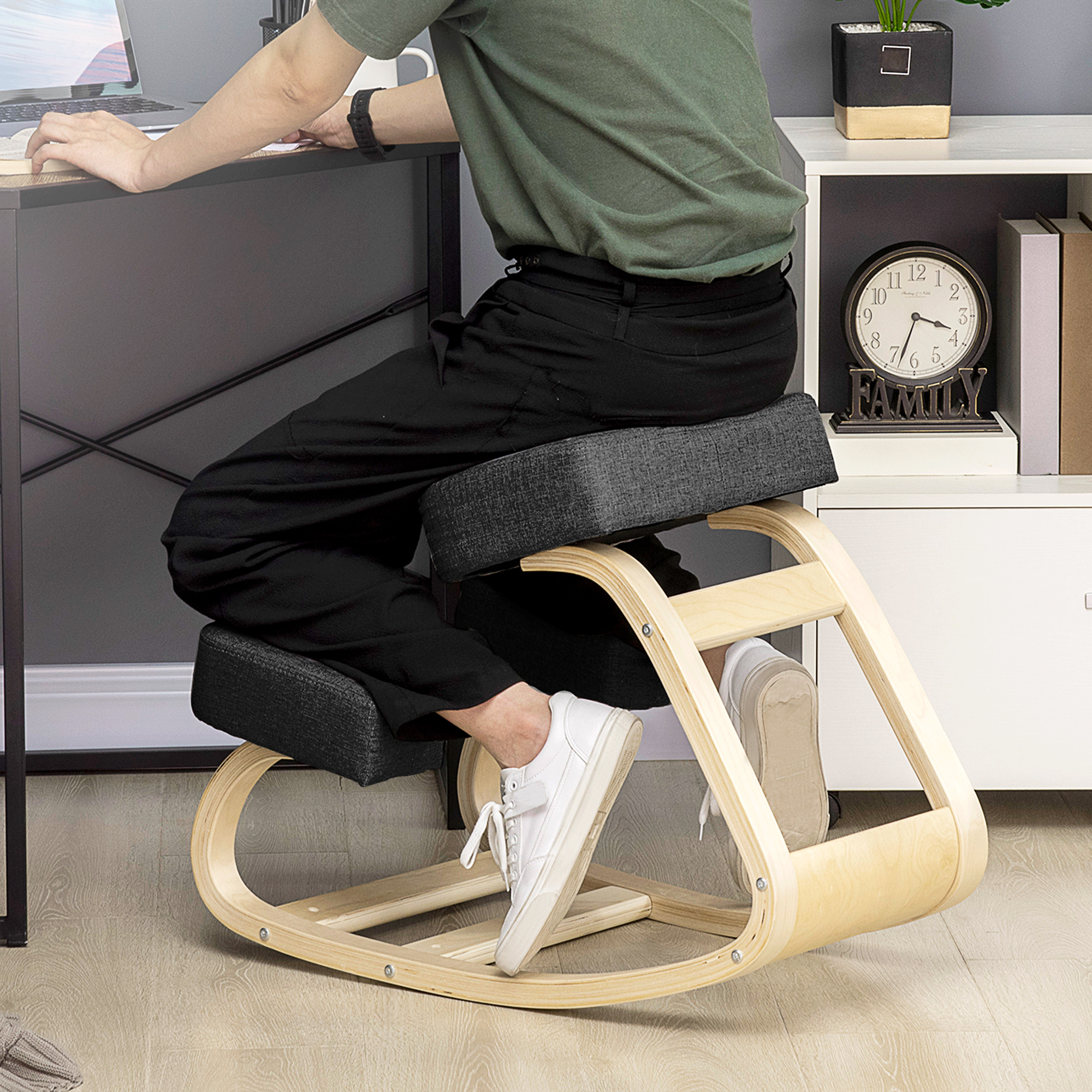 Una persona inginocchiata su una sedia ergonomica in legno a una scrivania.