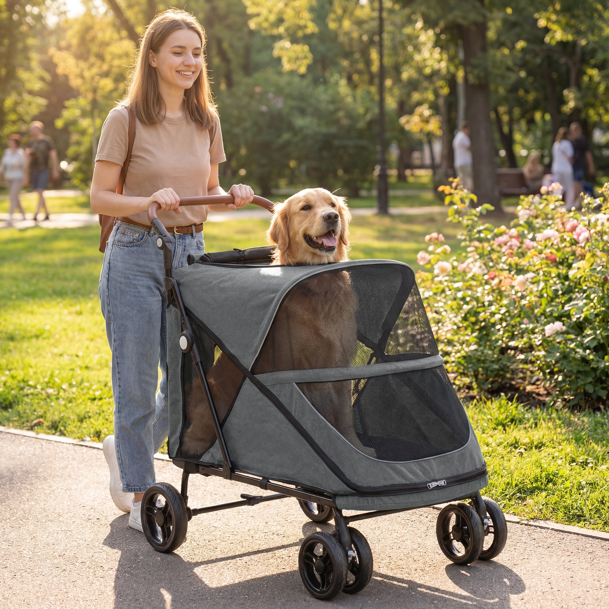 Una mujer en camiseta beige y jeans empuja un carrito gris para perros con un golden retriever dentro, en un parque.