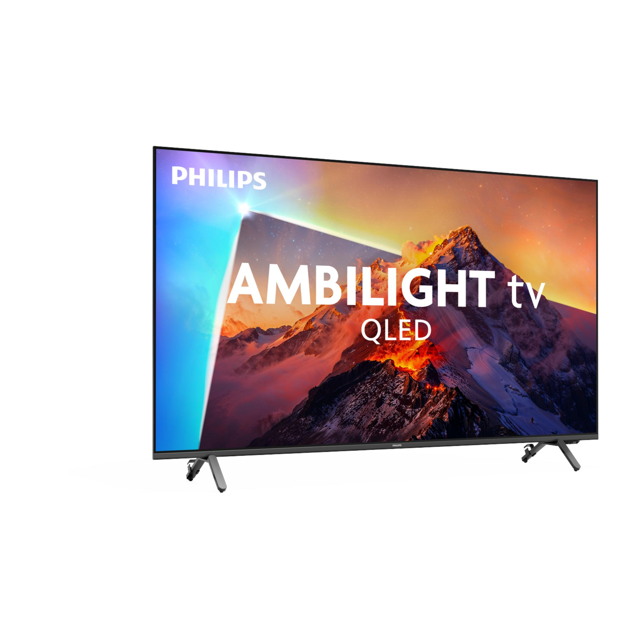 Telewizor Philips Ambilight QLED wyświetla górzysty krajobraz z jarzącym się niebem na ekranie.