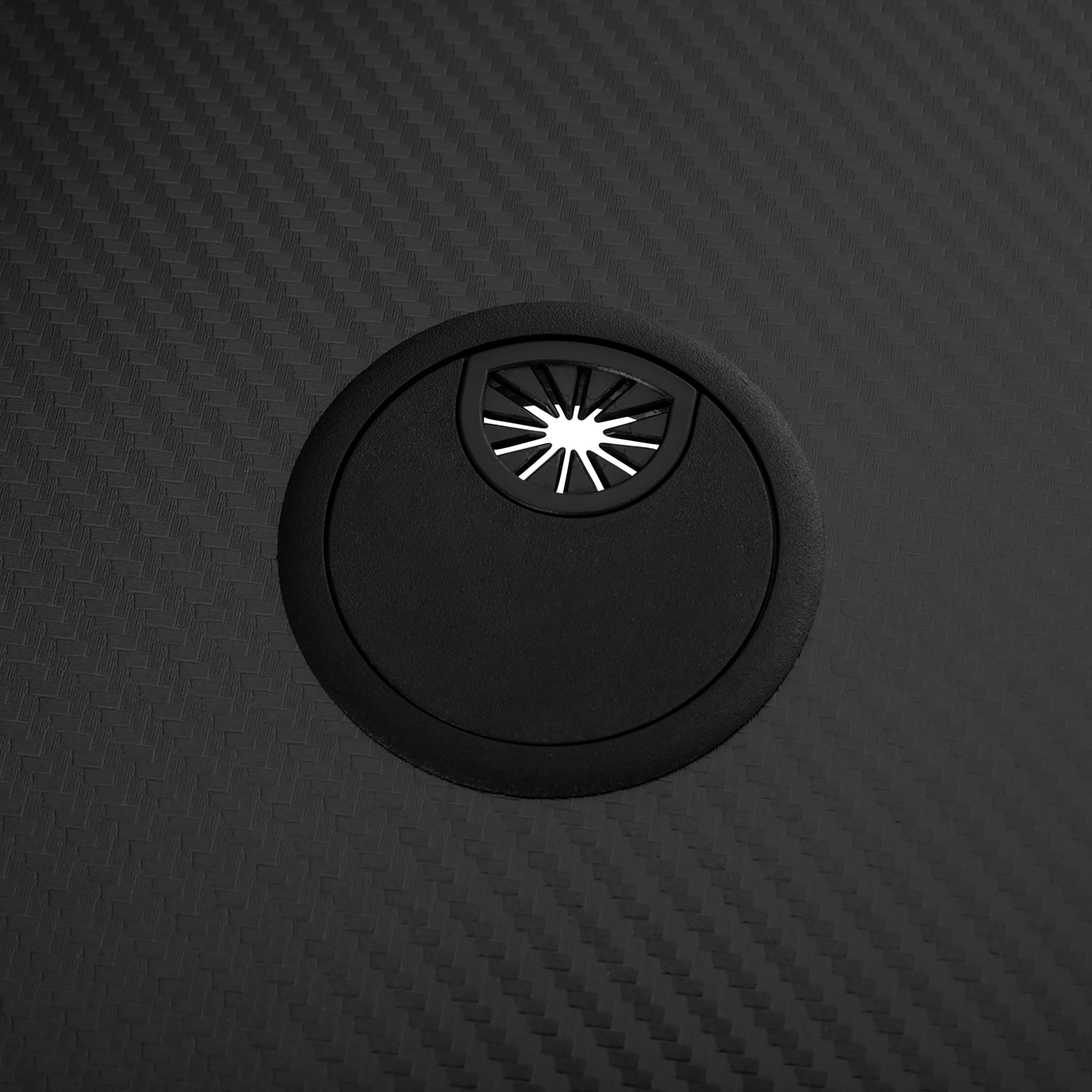 Schwarze Tischdurchführung mit einer Sternöffnung auf einer schwarzen Tischplatte im Kohlefaser-Design.