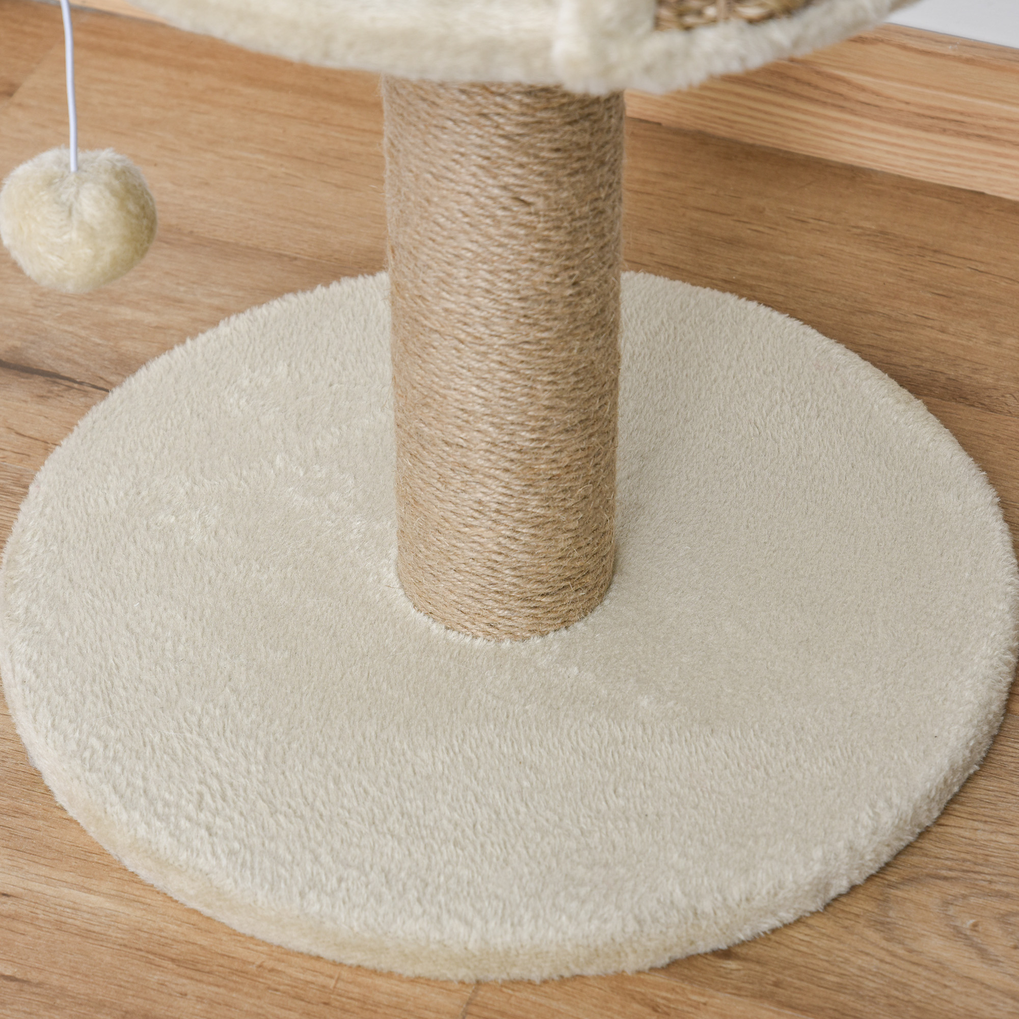 Una base de árbol para gatos beige con poste de sisal y juguete en suelo de madera.