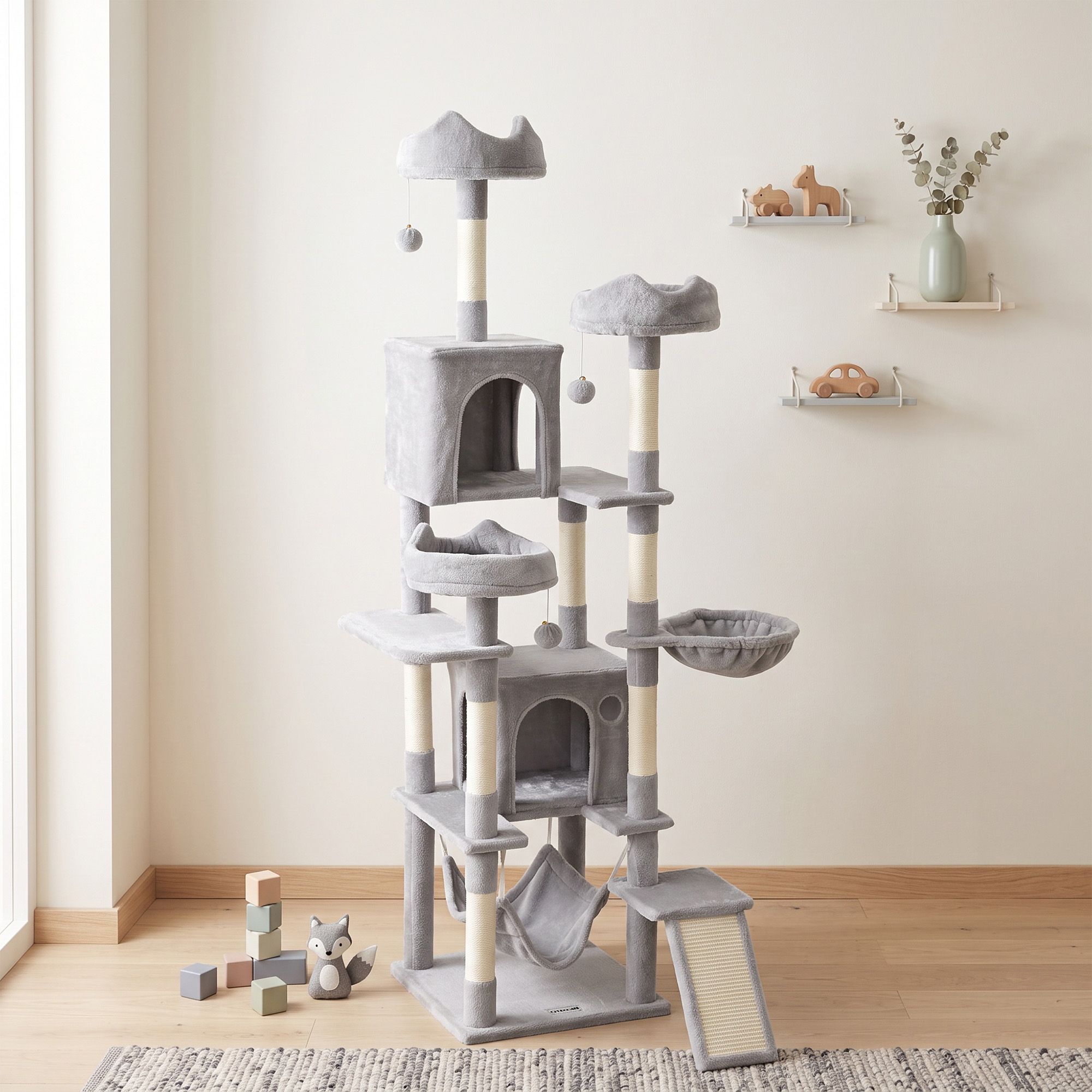 Un gran árbol para gatos gris con múltiples perchas, postes rascadores y juguetes colgantes en una habitación luminosa.