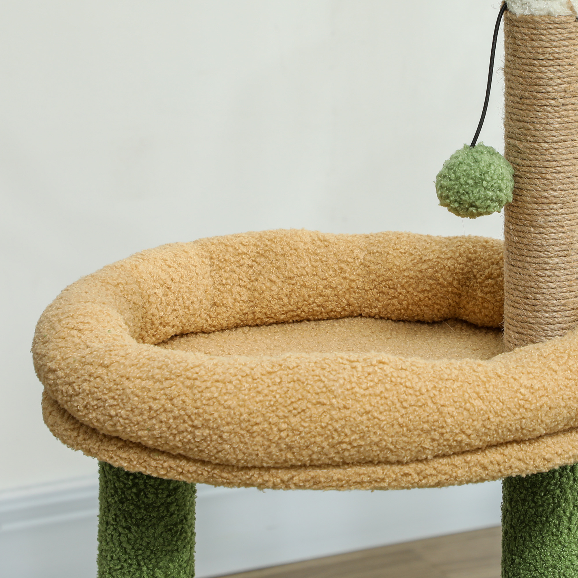 Cama de felpa beis para gatos con poste rascador y bola verde colgante.
