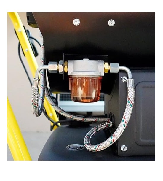 Un filtro de combustible con recipiente de cristal transparente y racores metálicos conectado a mangueras.