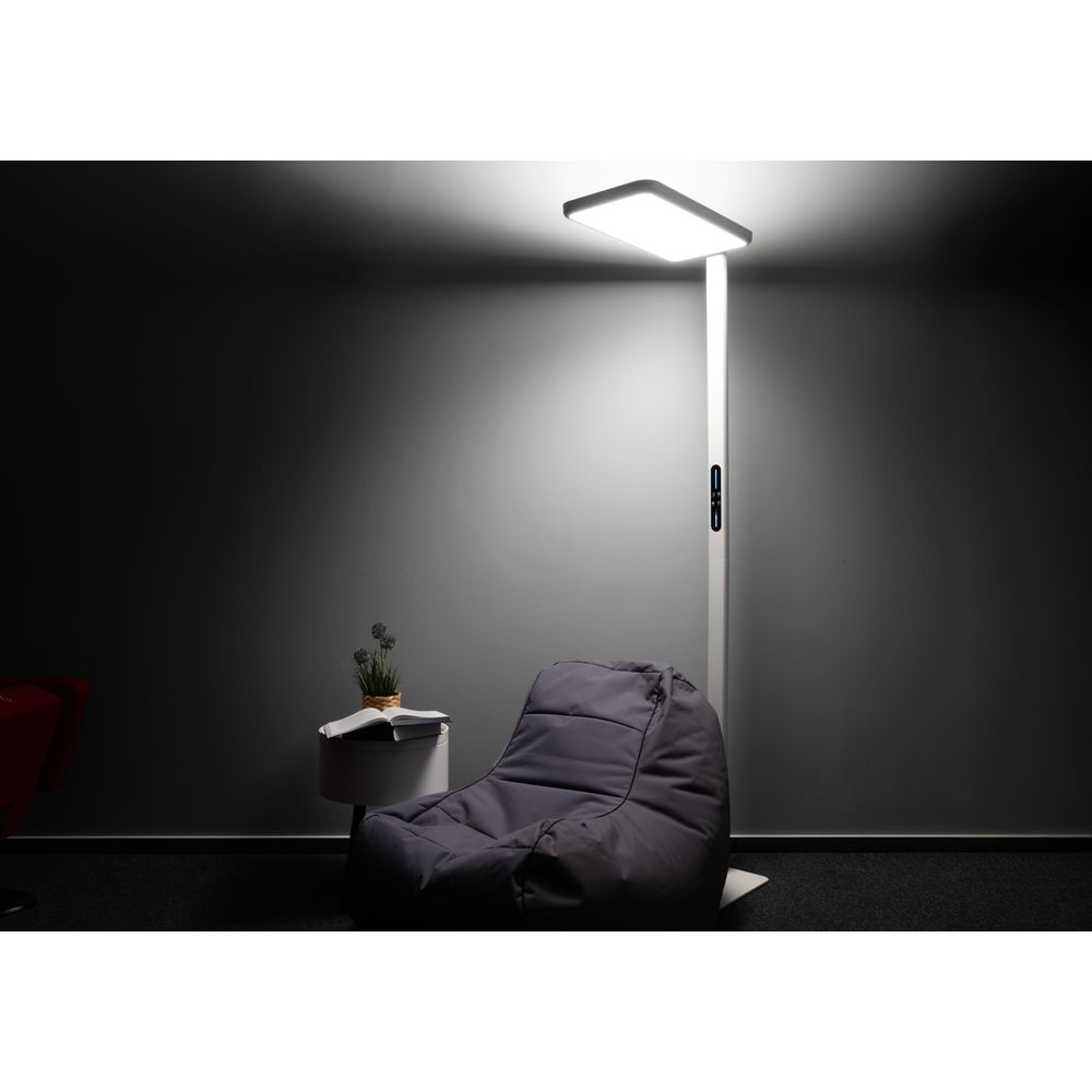Ein grauer Sitzsack, ein kleiner Tisch mit Buch und Pflanze, und eine helle Stehlampe in einem dunklen Raum.