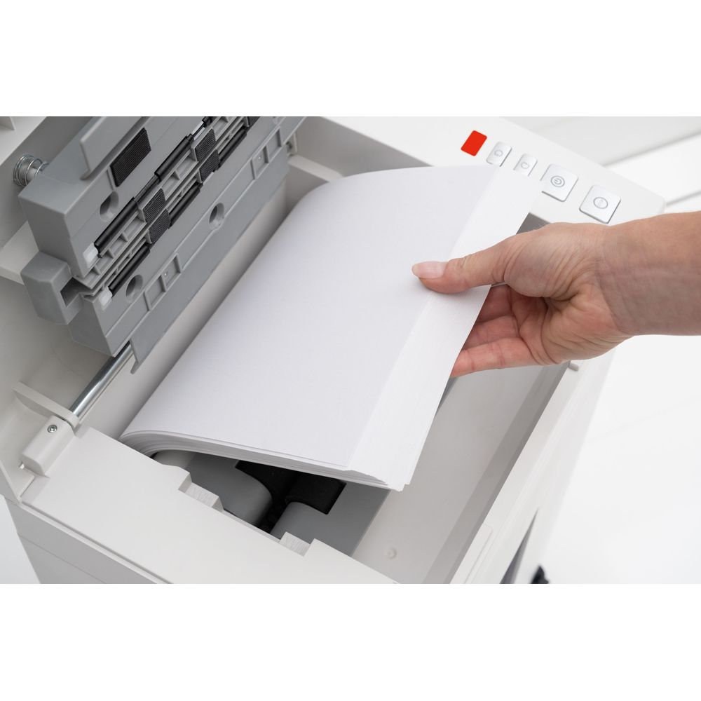 Eine Hand legt Papier in ein weißes Drucker- oder Scangerät ein.