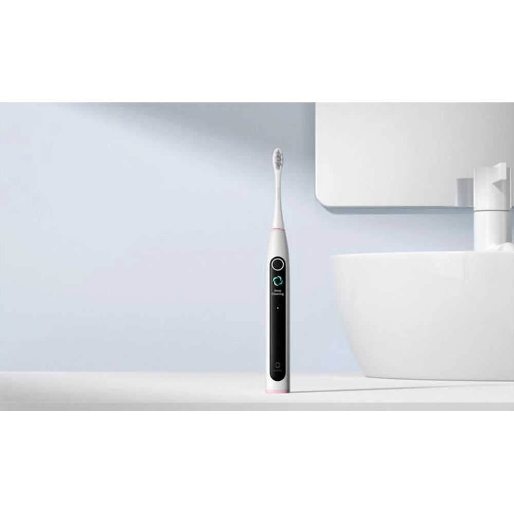 Uno spazzolino elettrico bianco con display digitale nero si trova su un ripiano in un bagno.