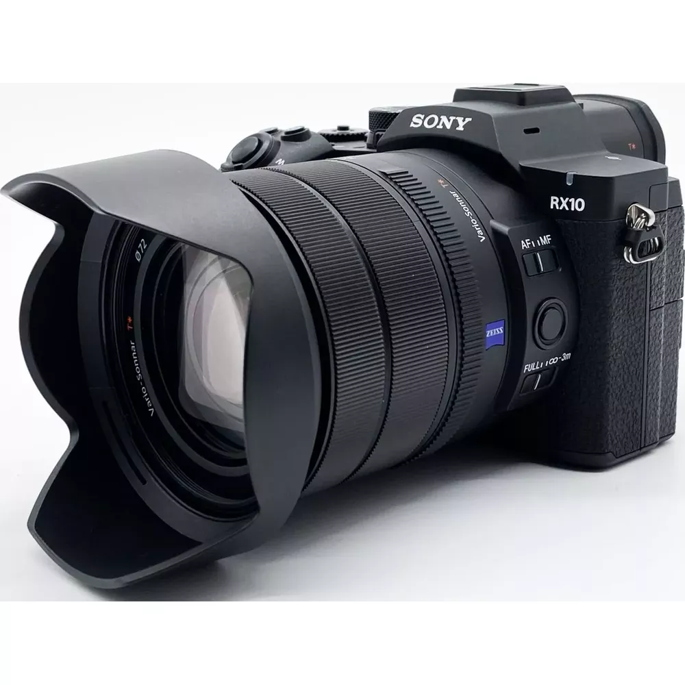 Een zwarte Sony RX10 bridgecamera met grote zonnekap op een witte achtergrond.