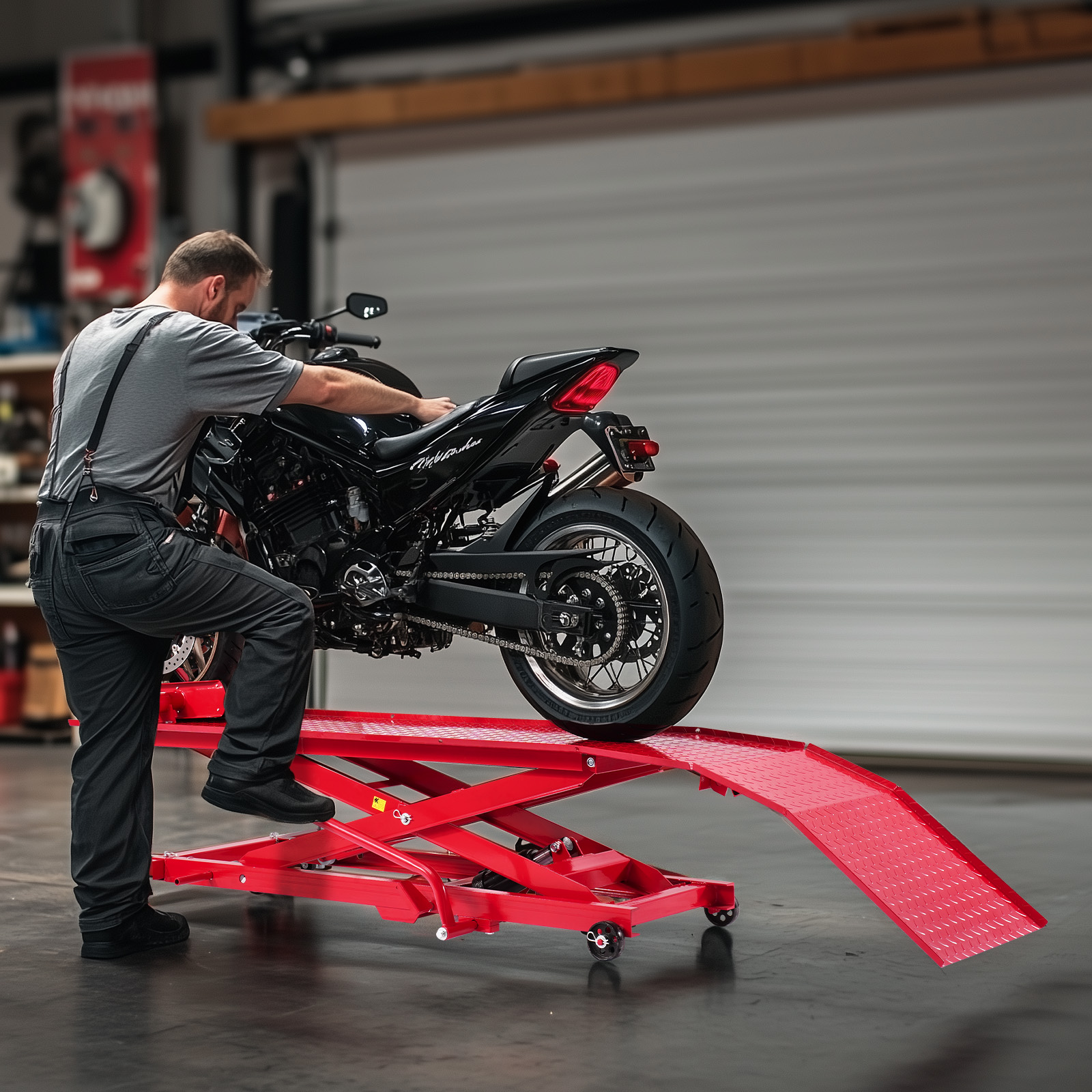 Mecánico trabajando en una motocicleta negra sobre una mesa elevadora roja en un taller.