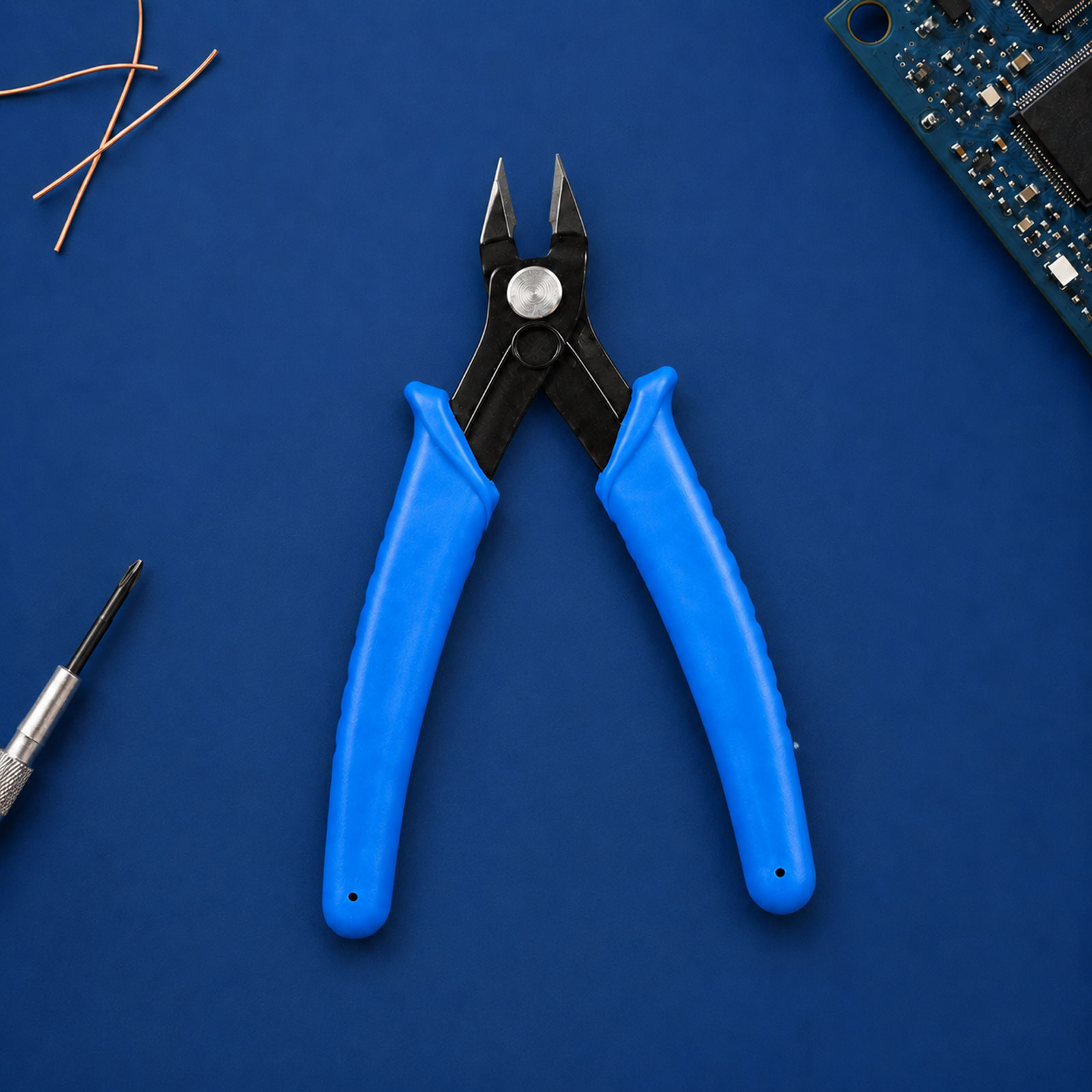 Blaue Seitenschneider auf blauem Untergrund, umgeben von Kupferdrähten und einer Platine.