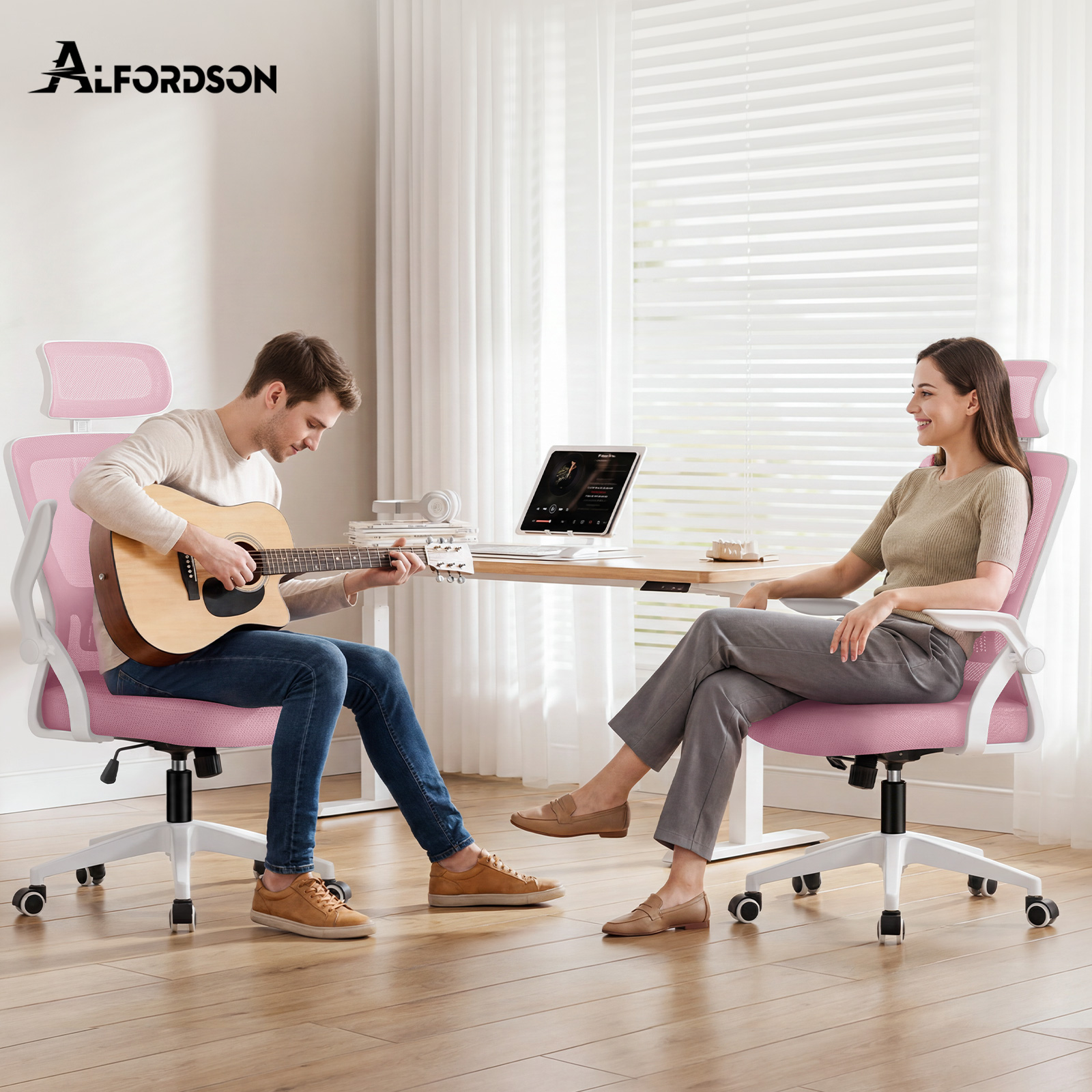 Ein Mann spielt Akustikgitarre und eine Frau sitzt ihm gegenueber an einem Schreibtisch, beide auf pinken Buerostuehlen.