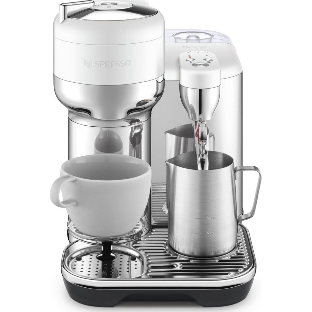 Une machine à café Nespresso blanche et chromée avec une tasse blanche et un pichet à lait.