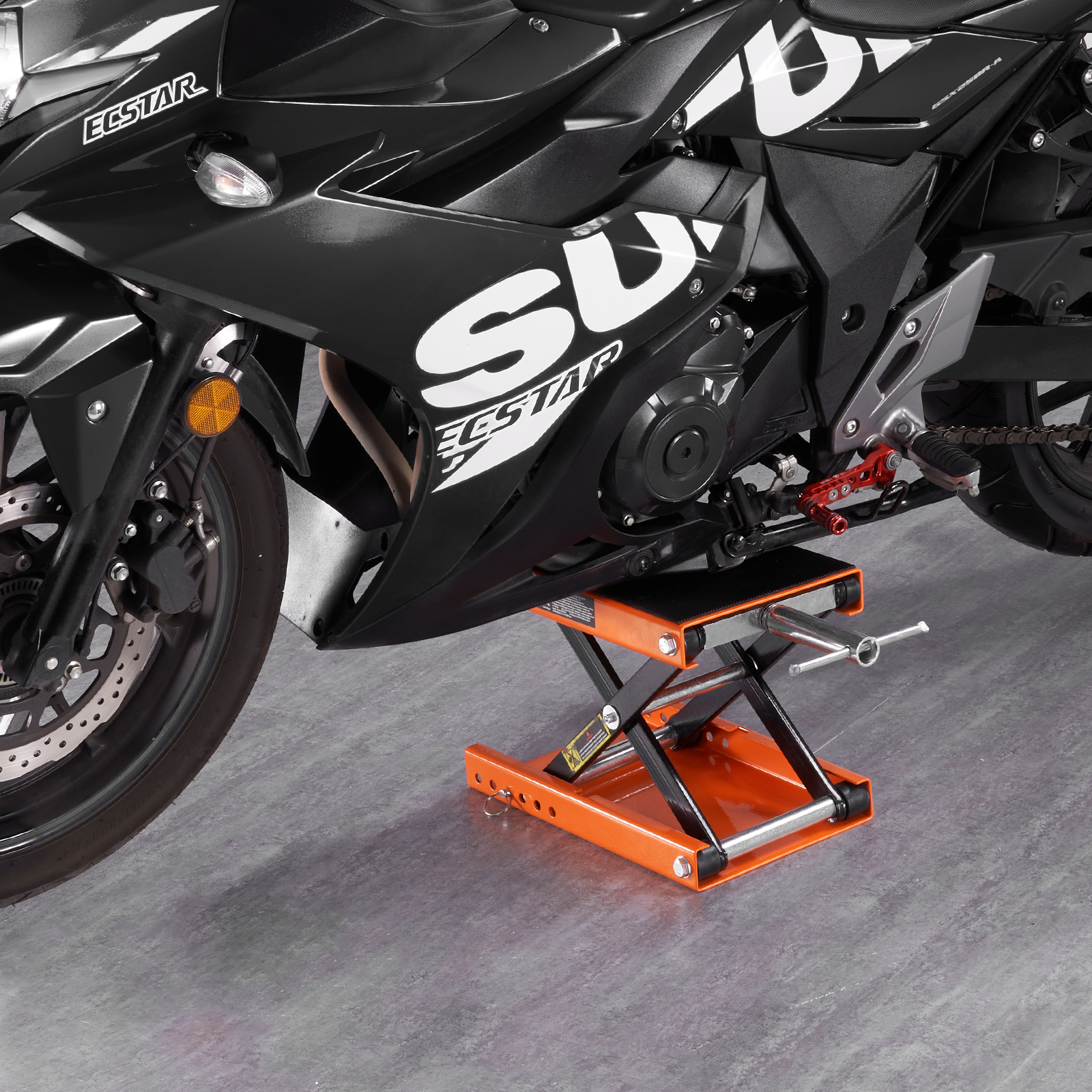 Una motocicleta Suzuki negra está elevada en un soporte elevador de tijera naranja y negro.