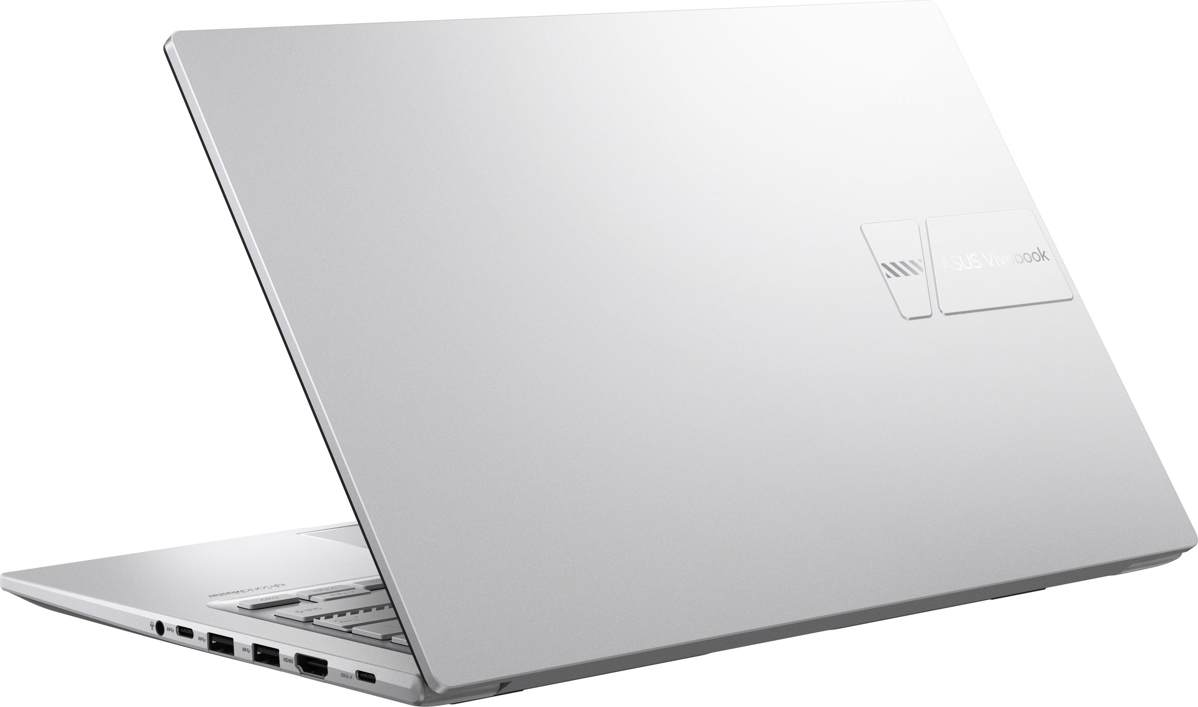 Un ordenador portátil ASUS Vivobook plateado con la tapa cerrada sobre una superficie blanca, mostrando puertos laterales.