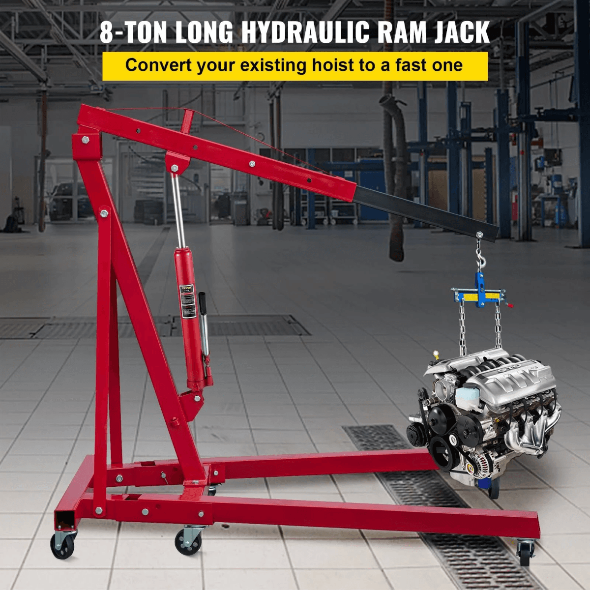 Una grúa de taller roja con ruedas levanta el motor de un coche en un taller mecánico.