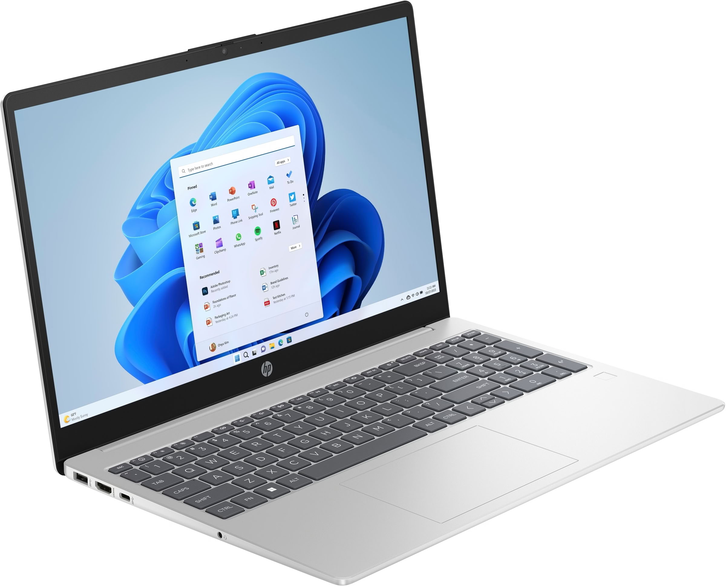 Una laptop plateada con el menú de inicio abierto en la pantalla sobre una superficie blanca.