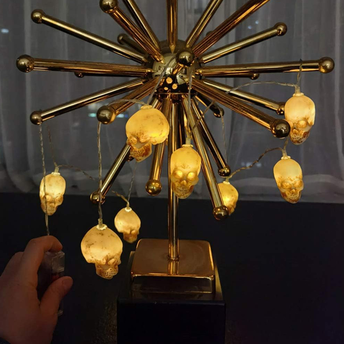Goldene Skulptur mit Totenkopf-Lichterkette auf einem Tisch.