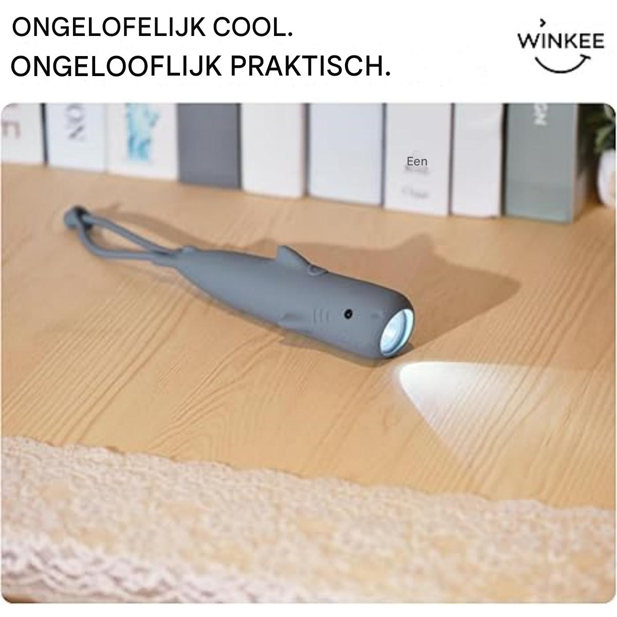 Eine graue wal-förmige Taschenlampe auf einem Holztisch wirft einen hellen Lichtstrahl.