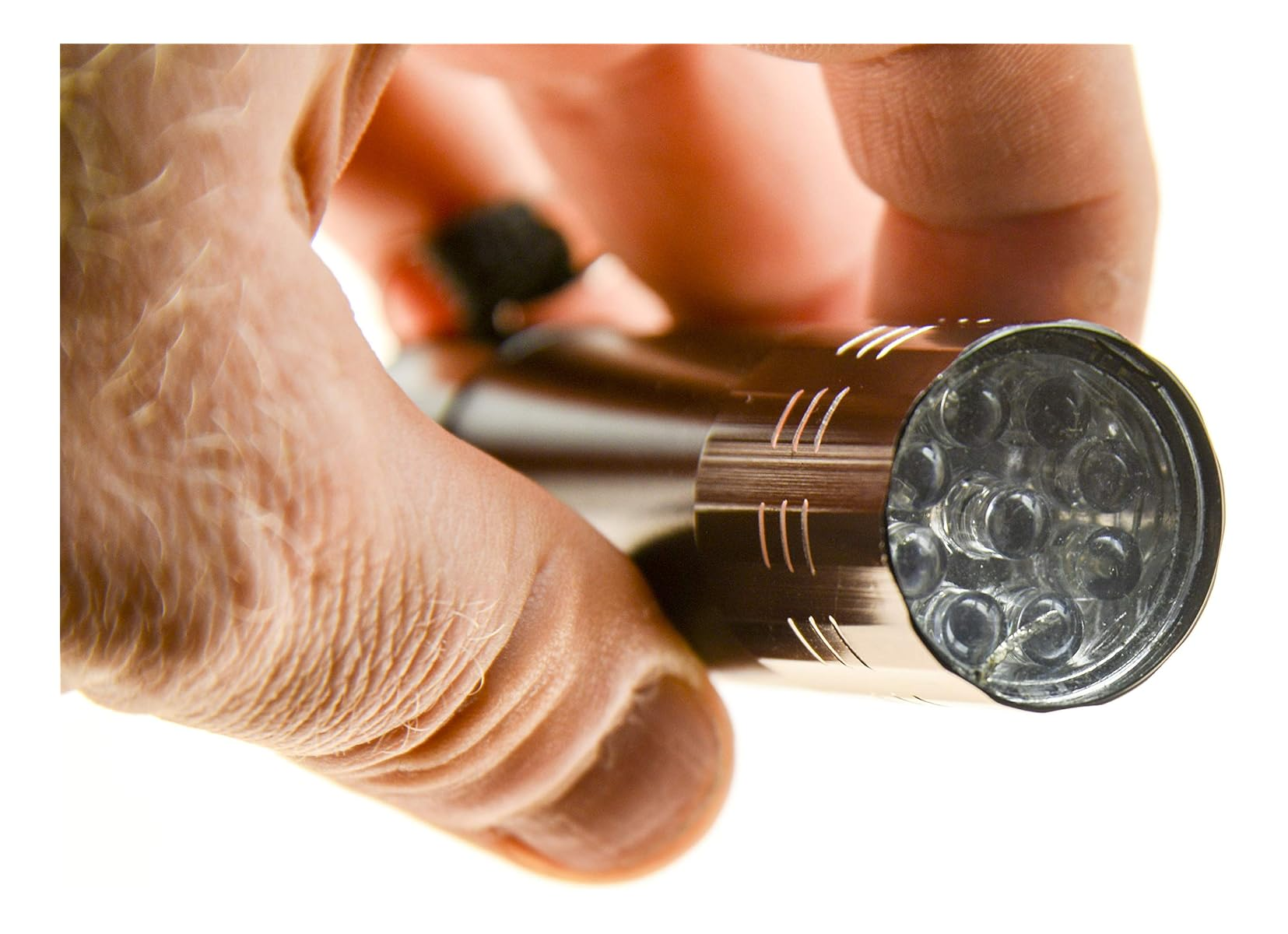 Eine Hand hält eine kleine, dunkle Metall-LED-Taschenlampe vor weißem Hintergrund.