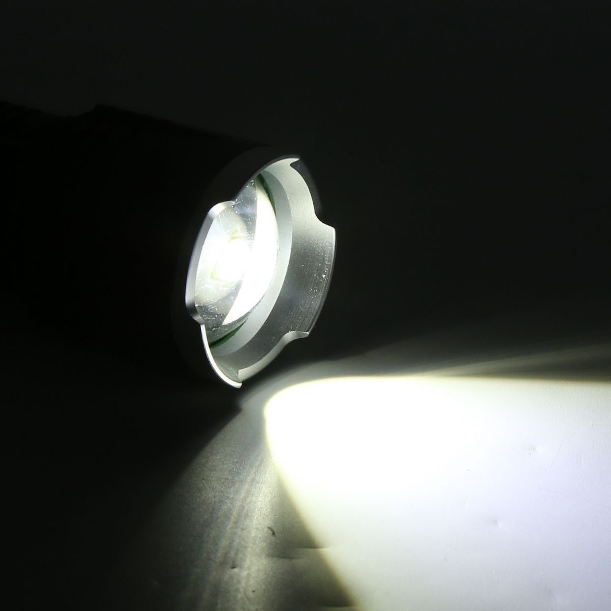 Eine eingeschaltete schwarze Taschenlampe wirft einen hellen Lichtstrahl in die Dunkelheit.